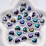 Many colorful heart-shaped beads rest inside of a bowl.