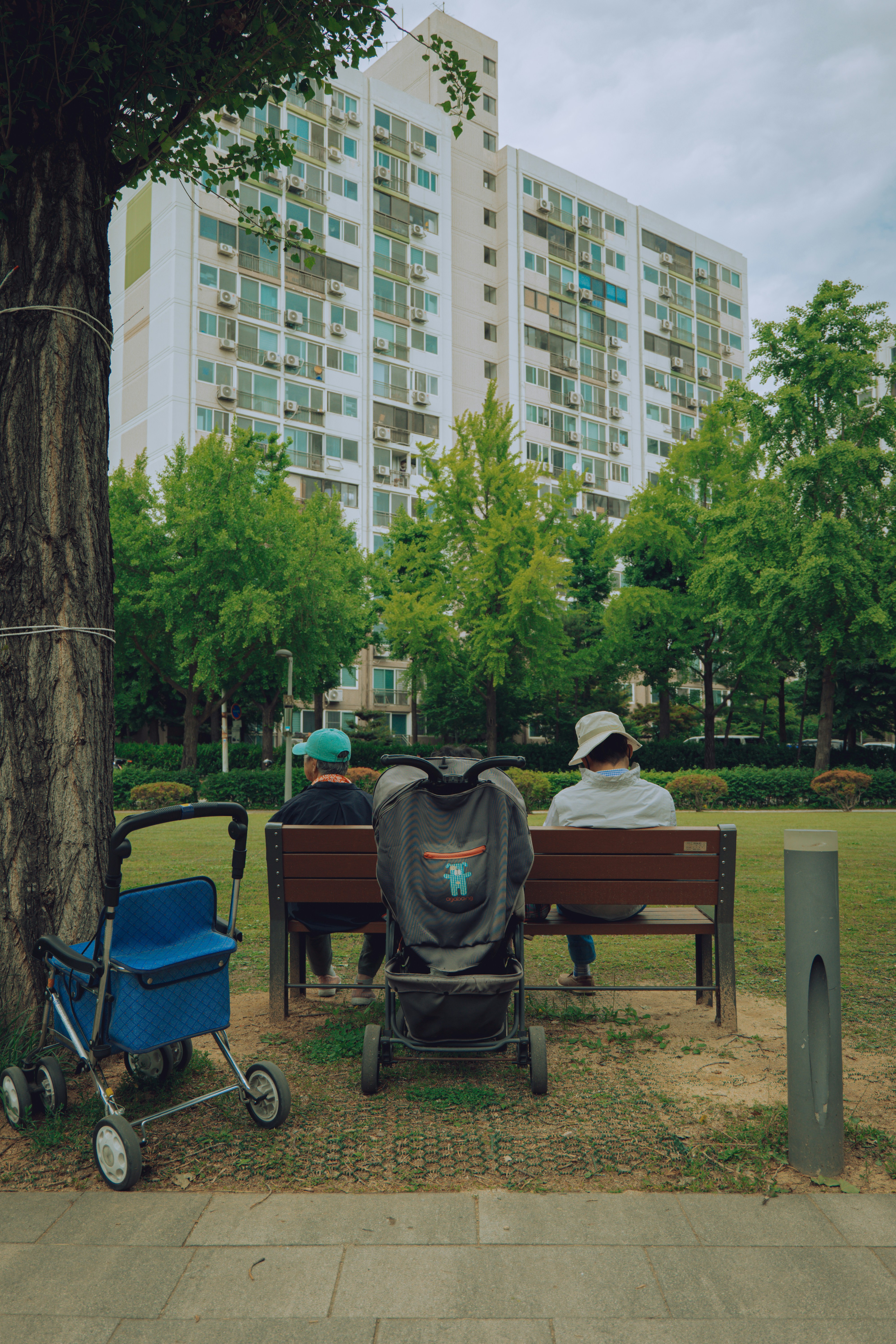 Two people sit on a bench in front of a building.