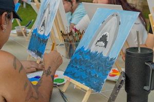 People paint shark artwork at an art class.