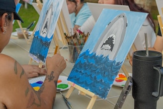 People paint shark artwork at an art class.