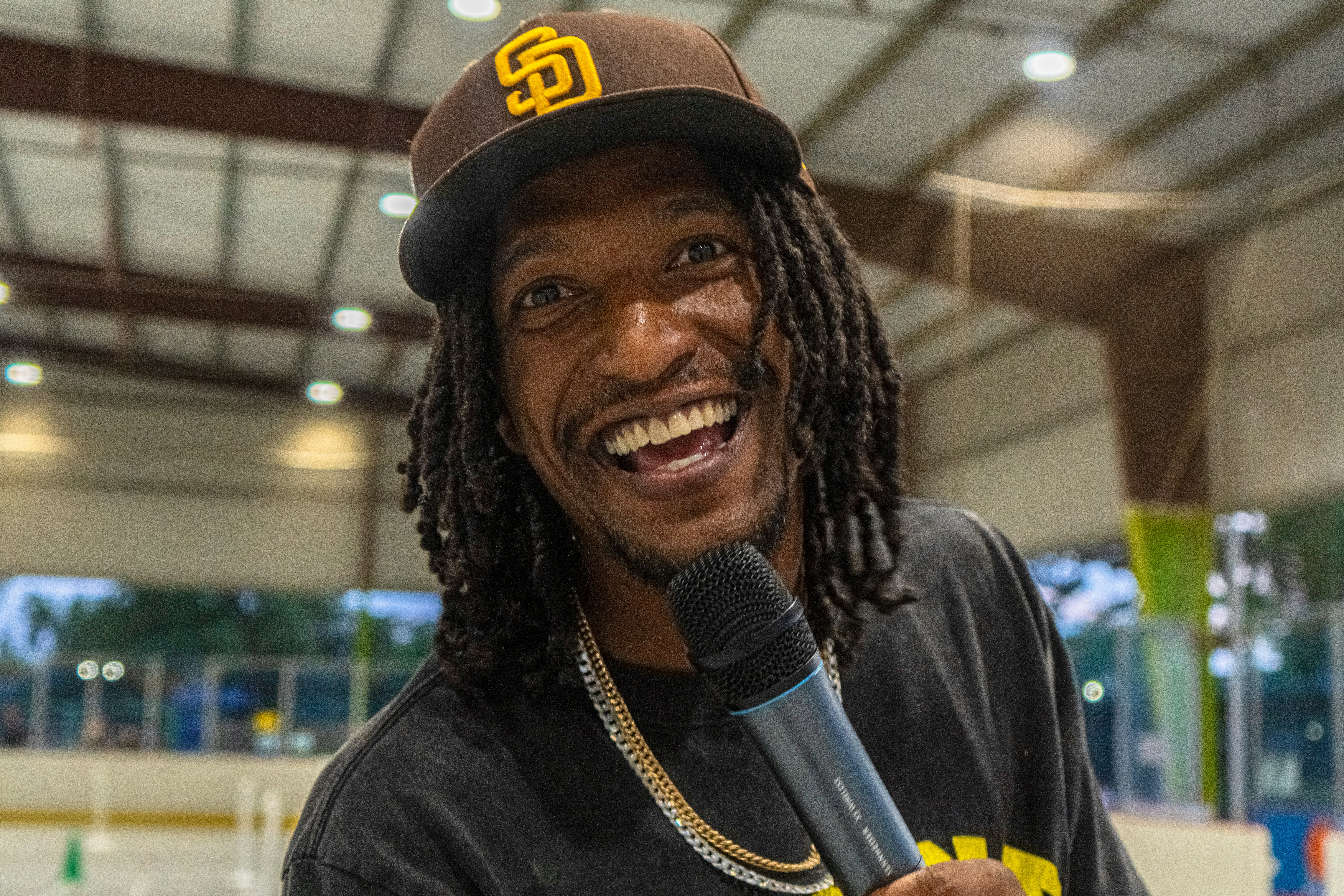 NBA draft stage podium microphone - Man smiling and holding a microphone indoors.