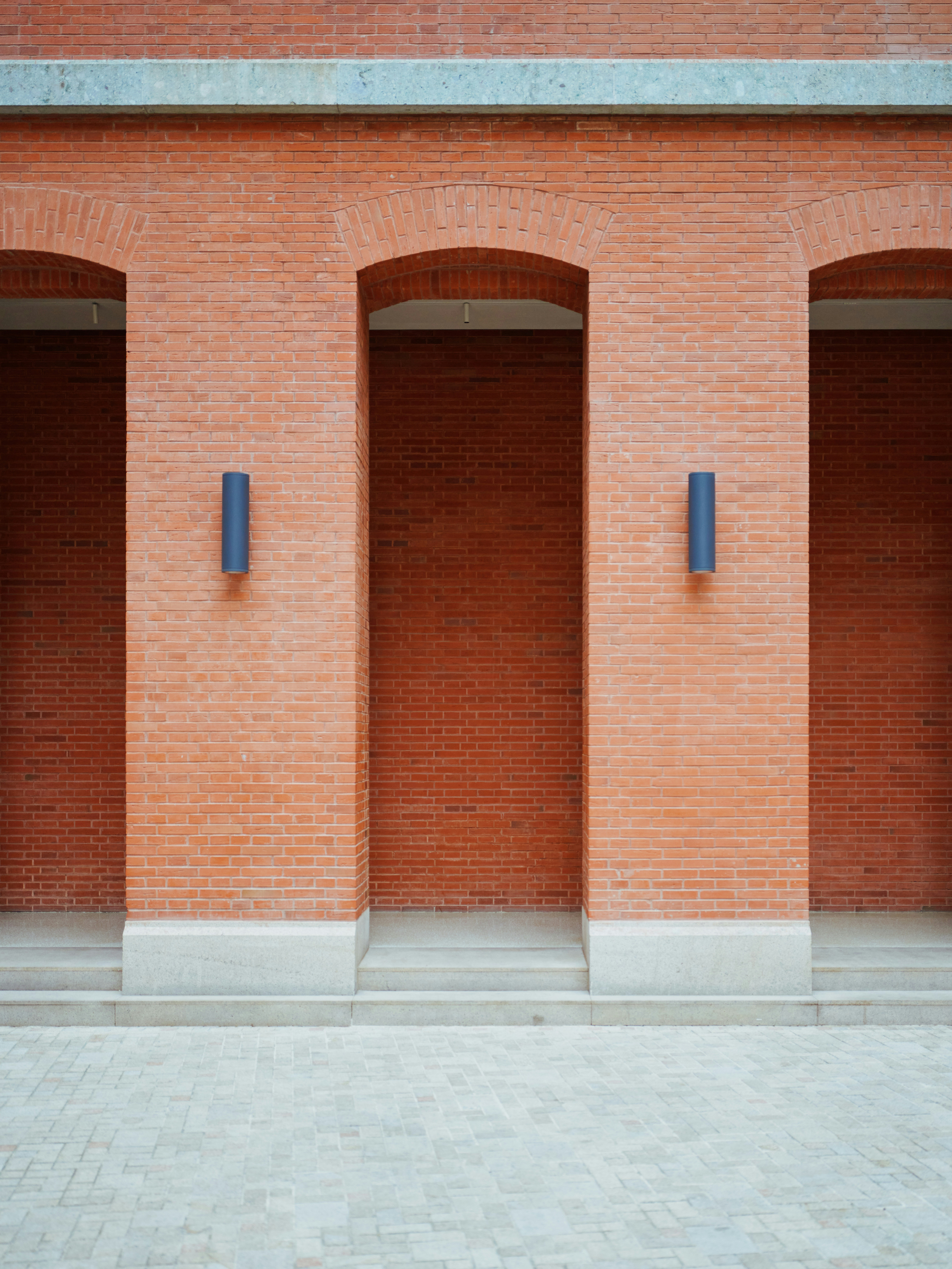 Eine rote Backsteinmauer mit drei Torbögen.
