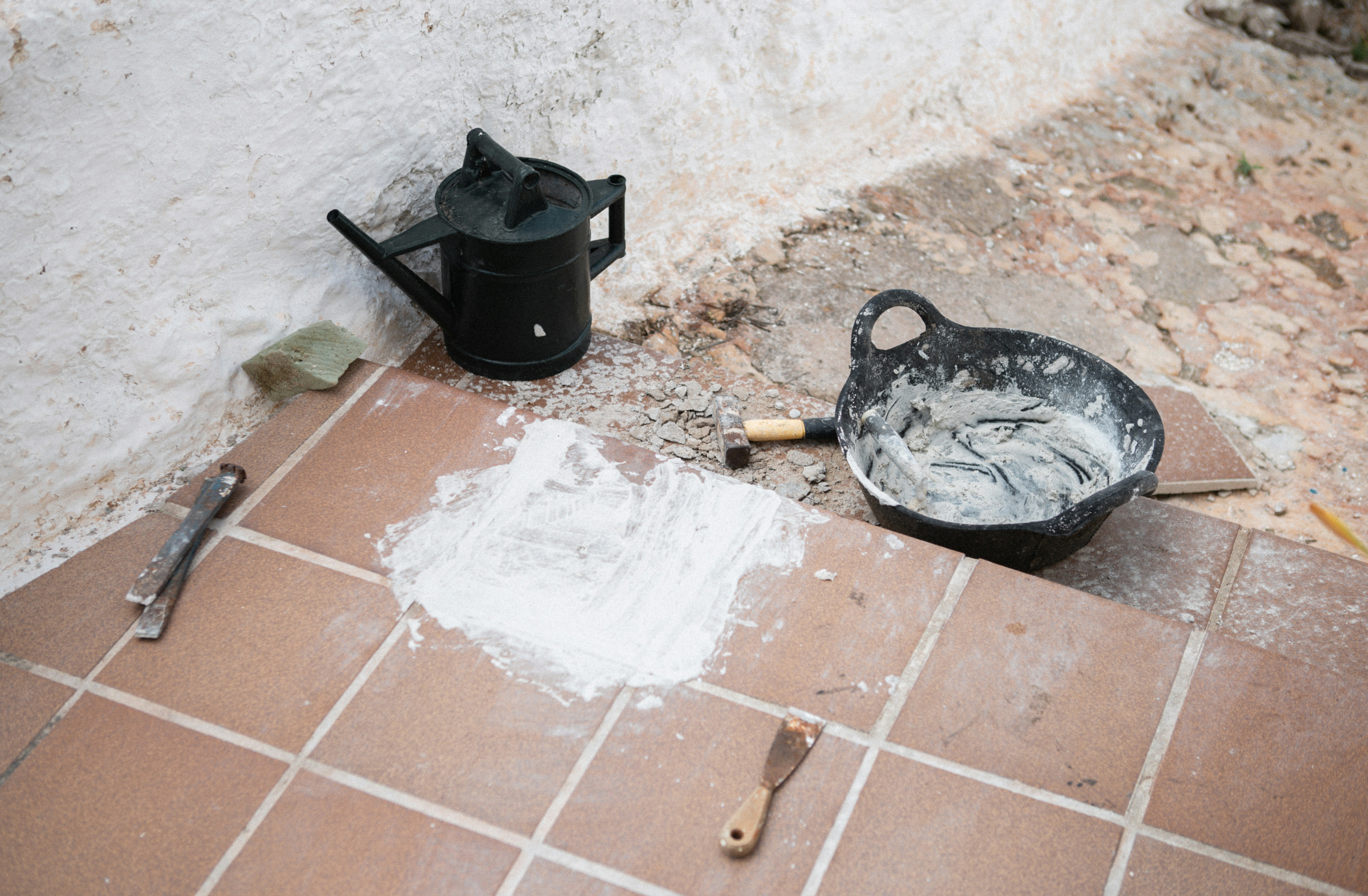 Tiling tools and materials are staged on the floor.