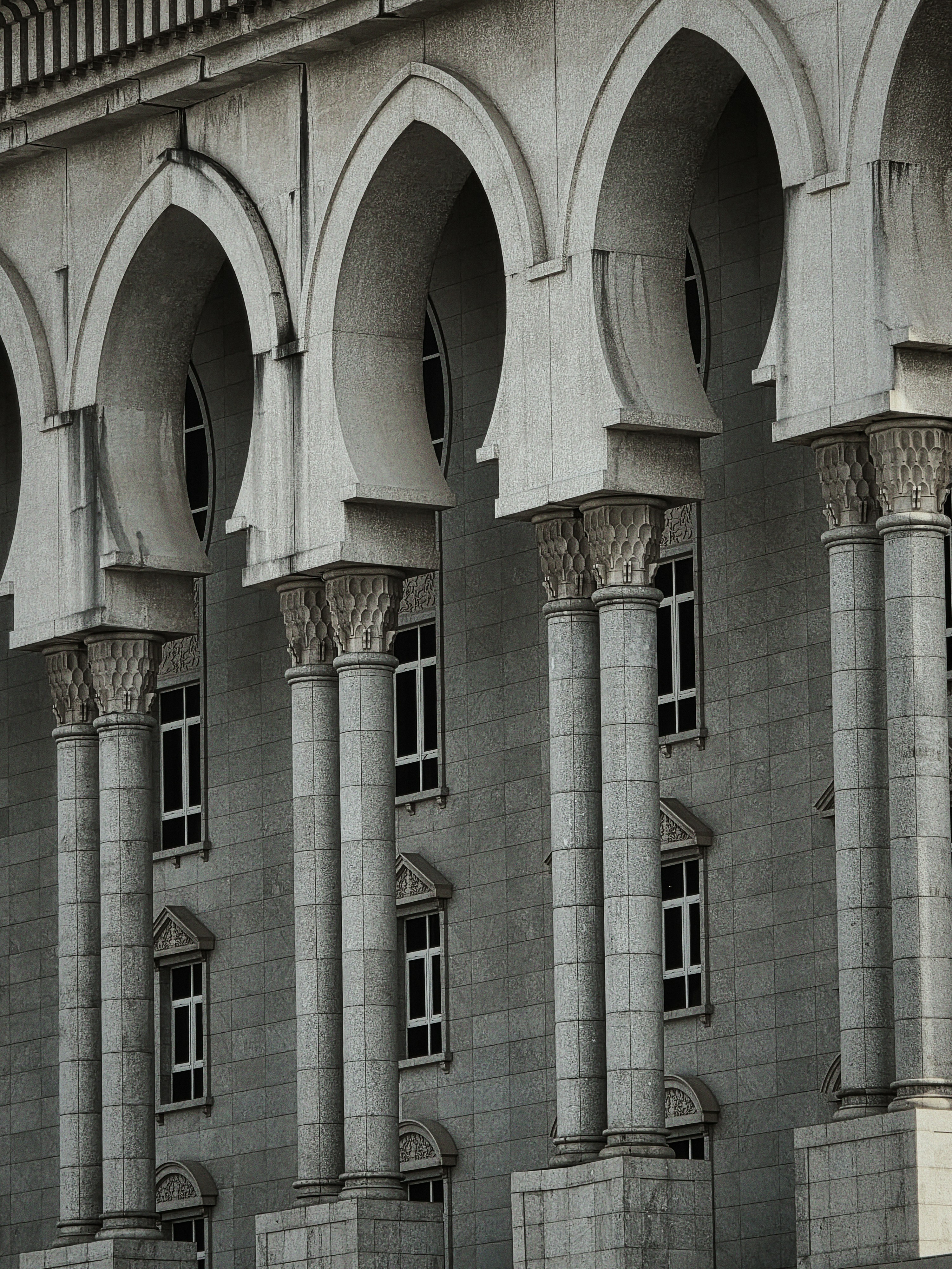 Columnas arqueadas adornan la fachada gris de un edificio.