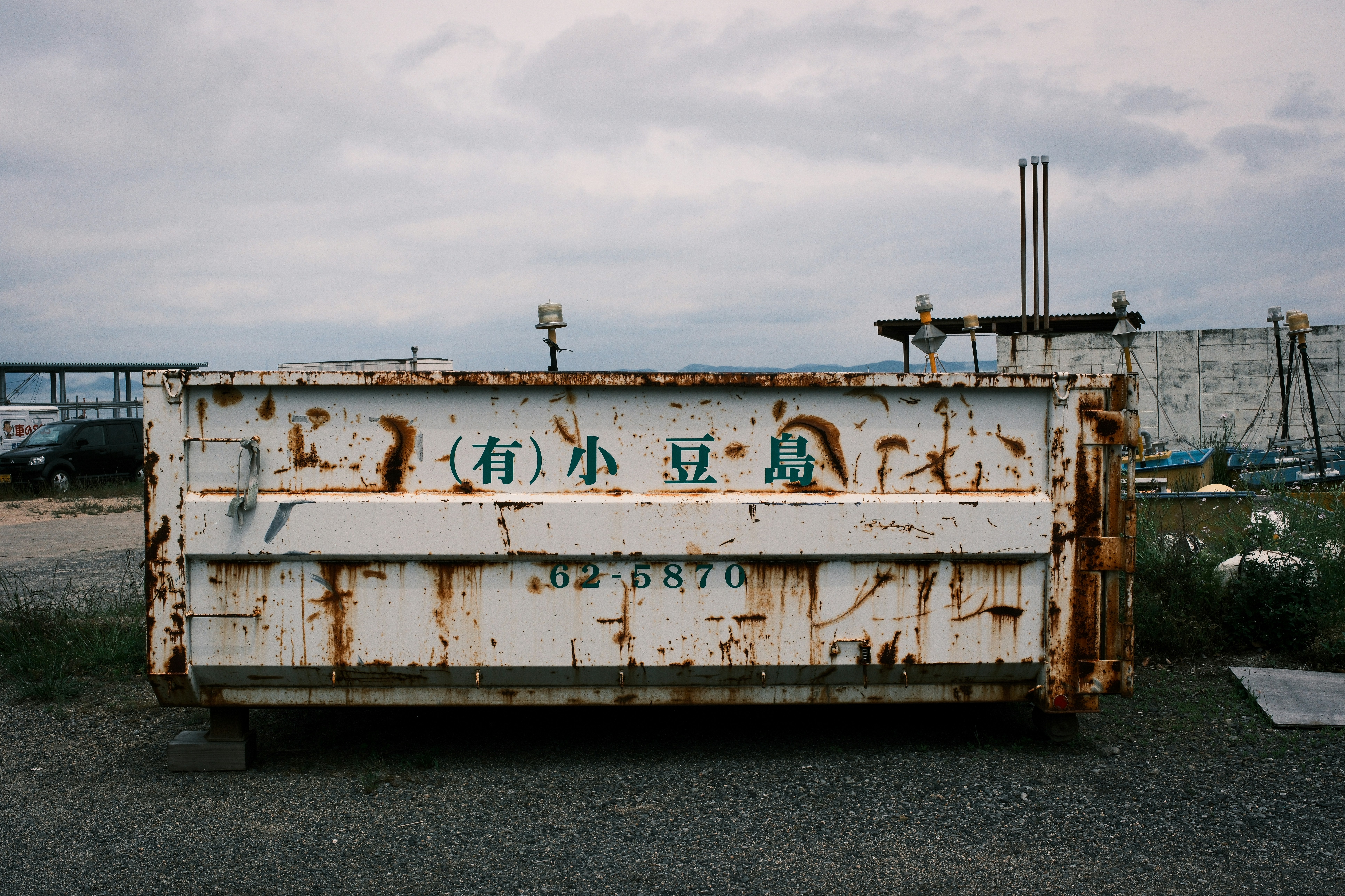 Rusty dumpster sits in an industrial outdoor area.