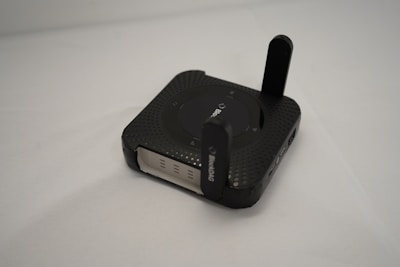 A black router sits on a white surface.