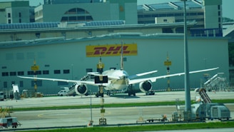An airplane is parked in front of a dhl building.
