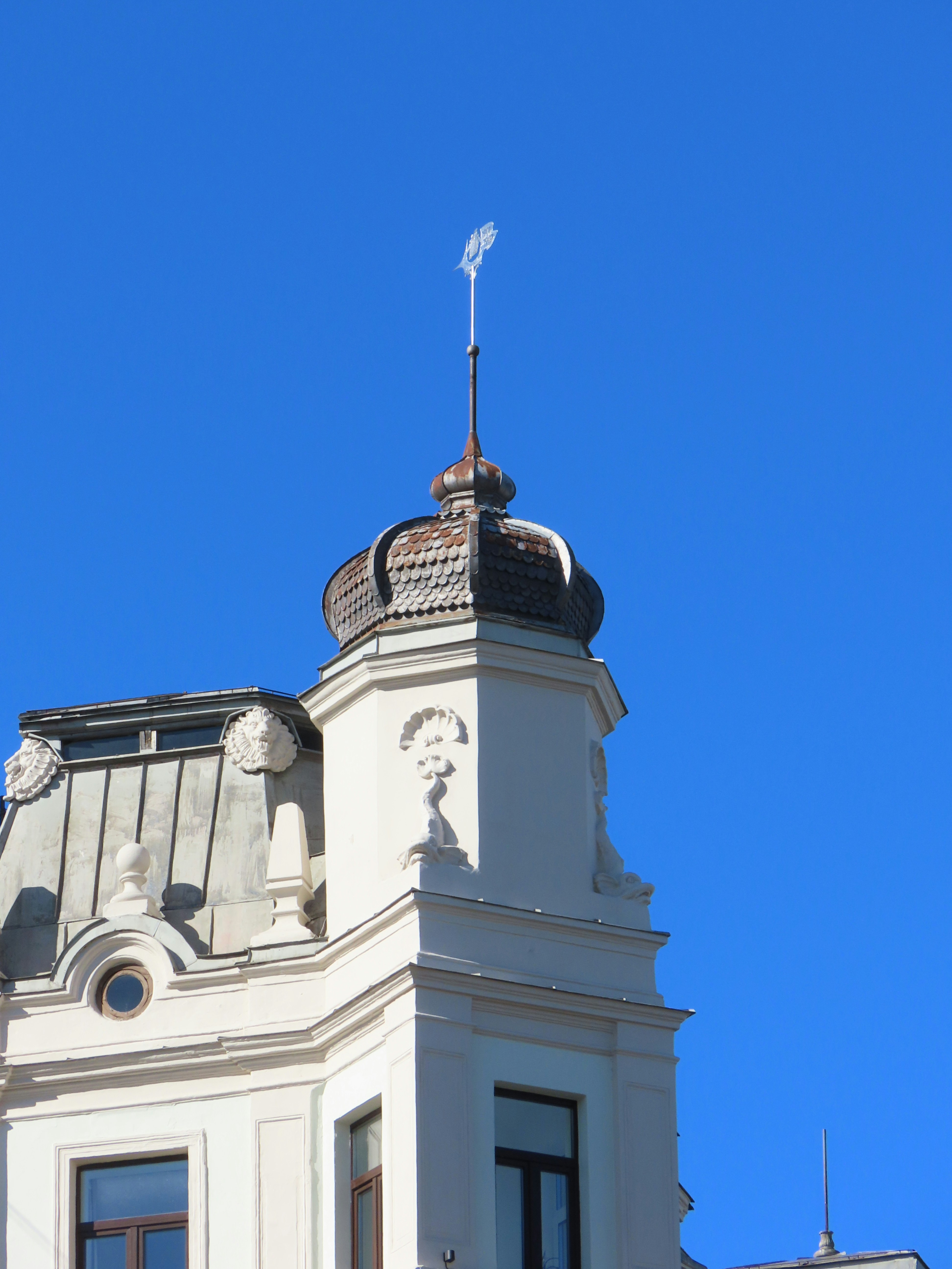 A white building tower reaches for the clear sky.