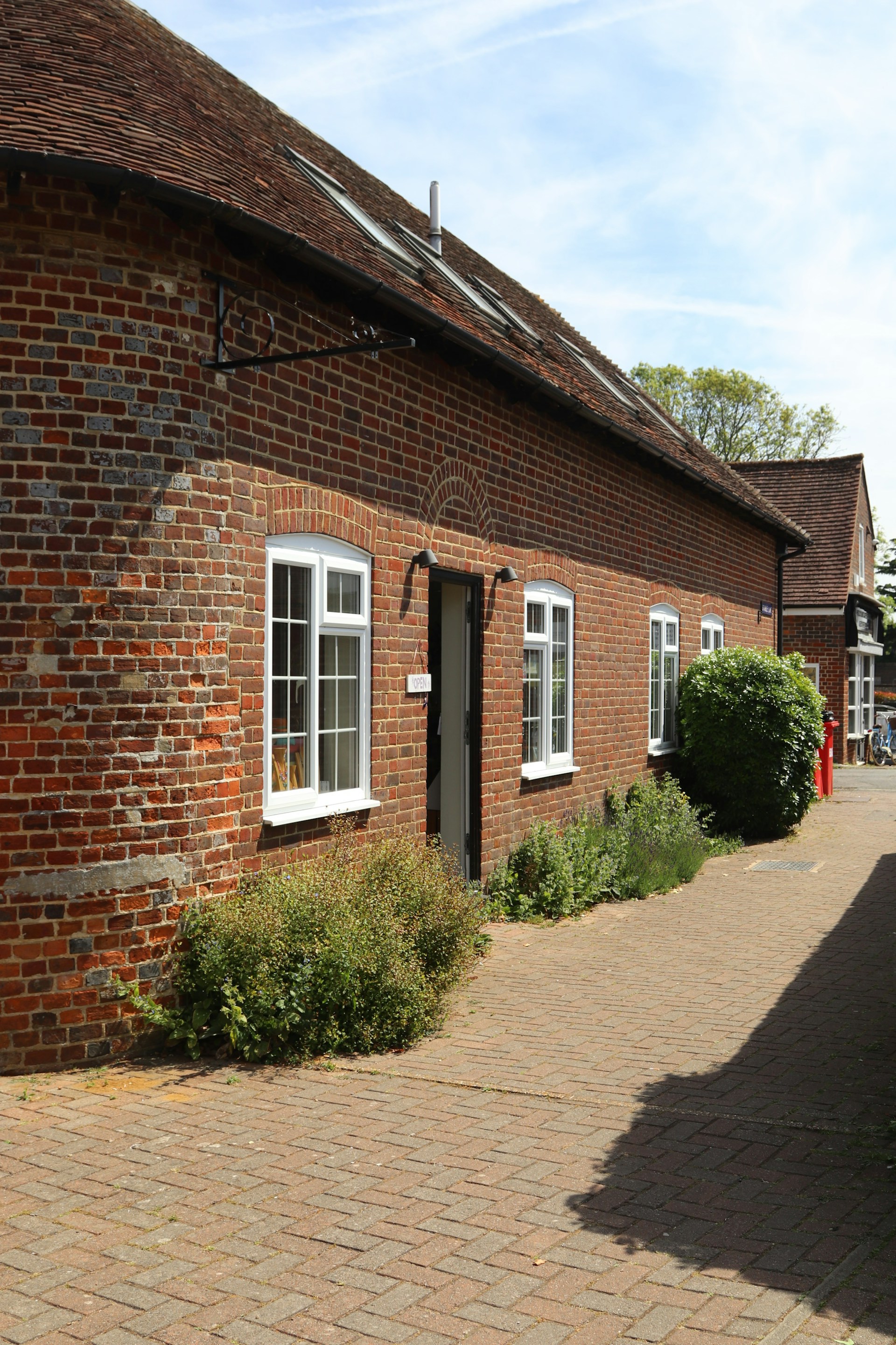 Brick building with white windows and paved path.