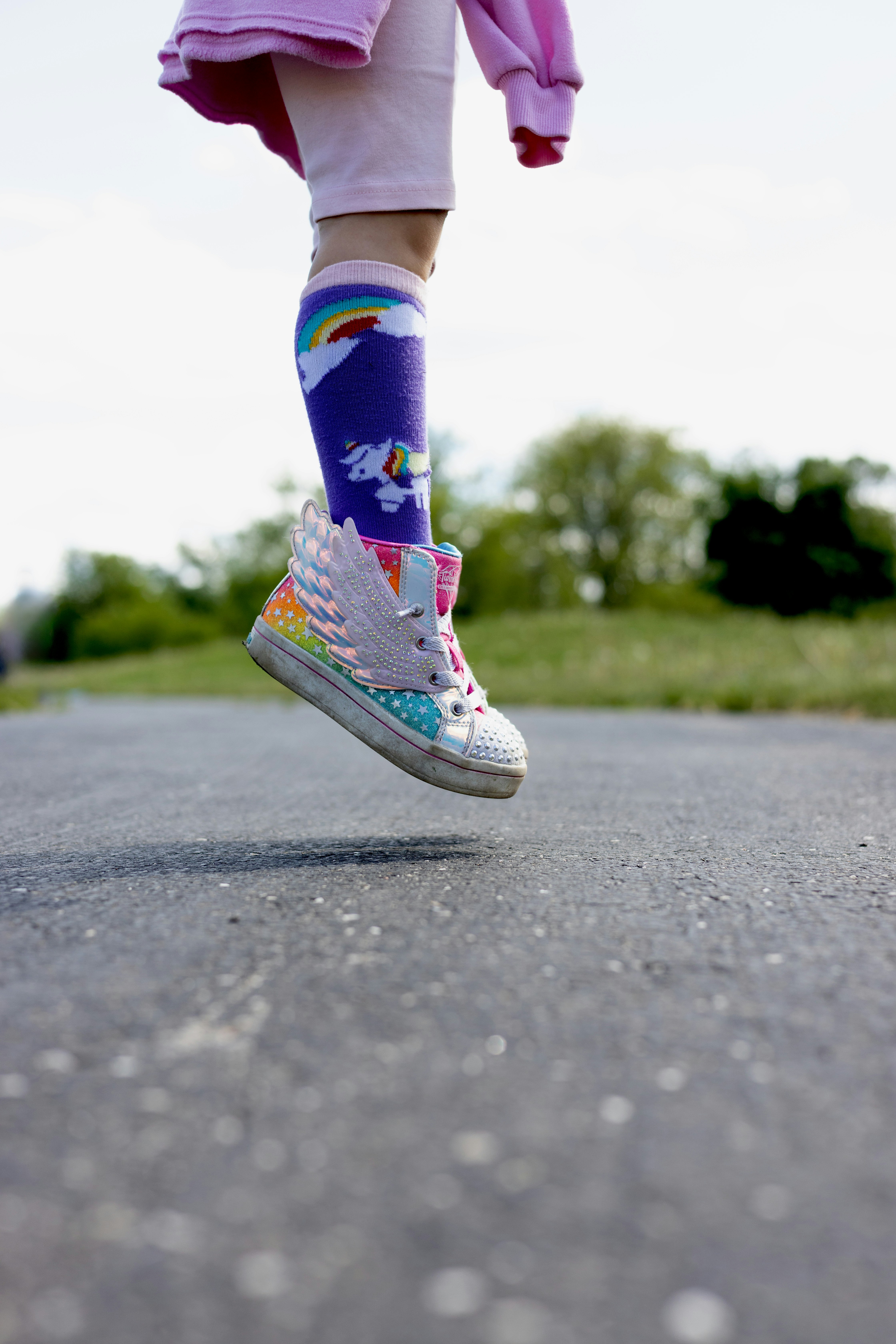 A child is jumping with a rainbow shoe.