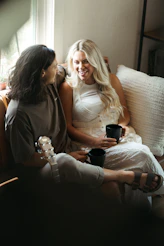 Two women relax with coffee and laughter.