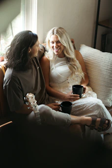 Two women relax with coffee and laughter.