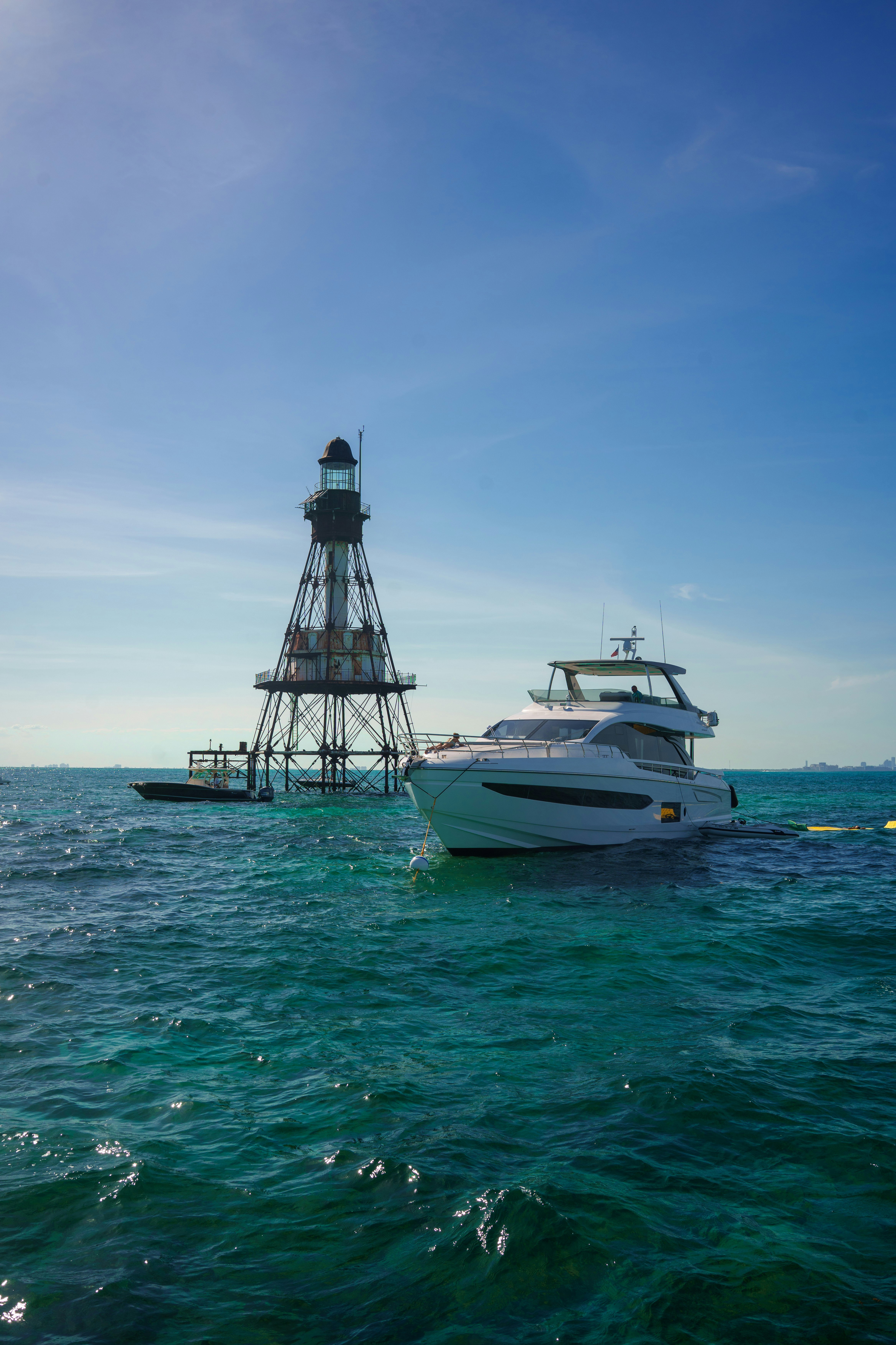 A yacht sails near a metal beacon.