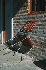 A chair leans against a brick wall.