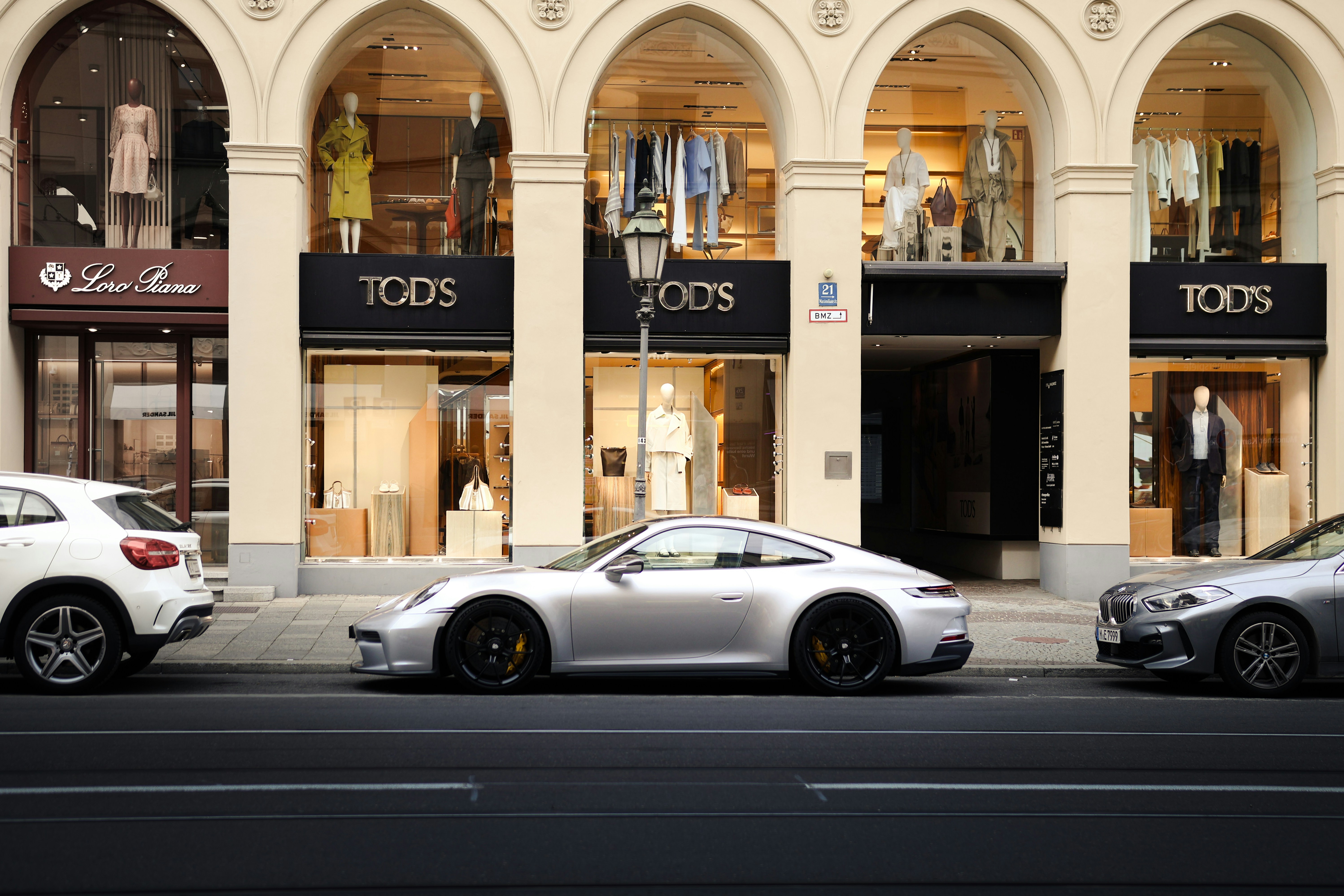 Luxury cars parked in front of a designer store.