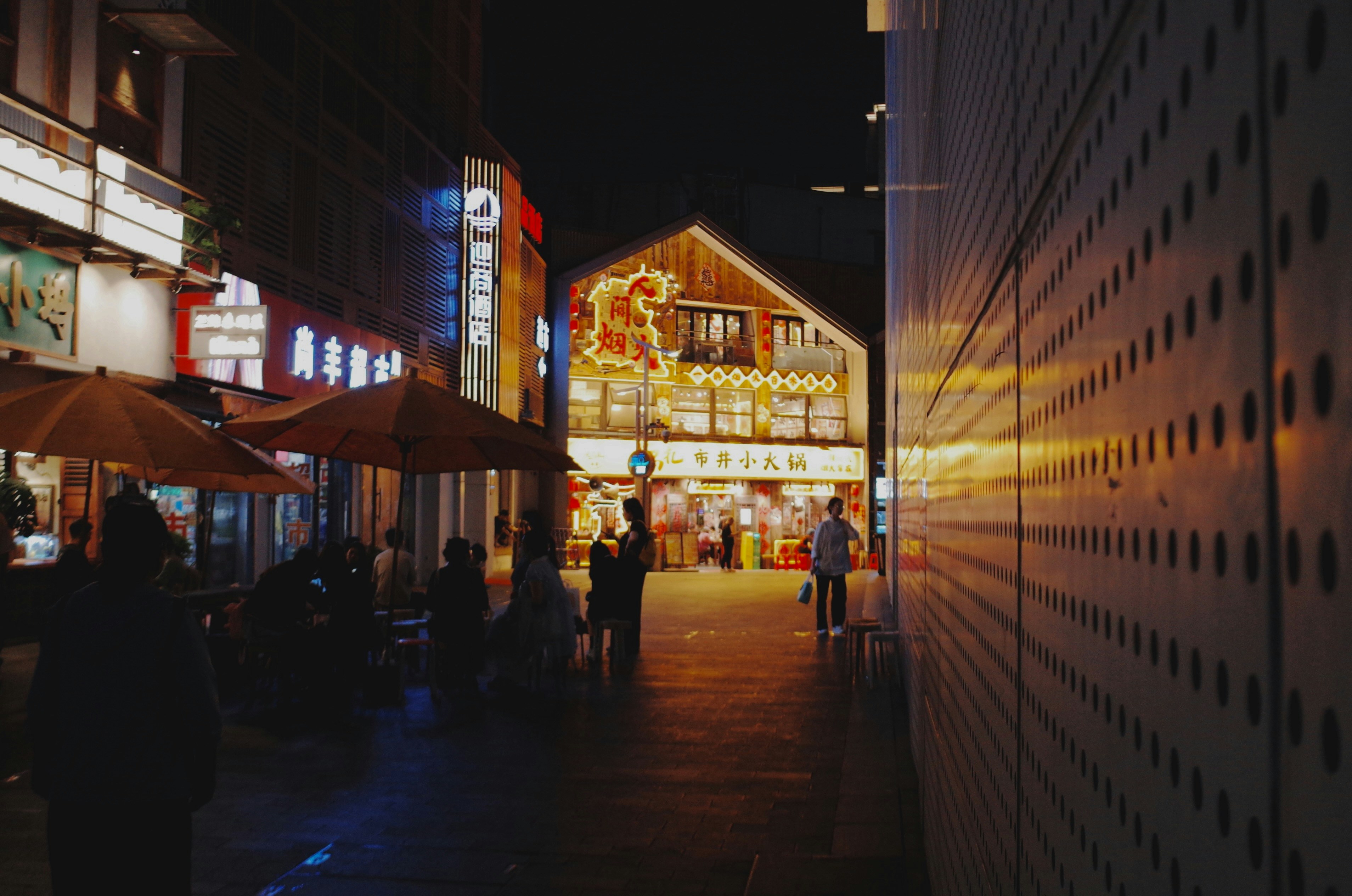 Nighttime street scene with shops and people.