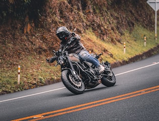 A motorcyclist leans into a curve on a road.