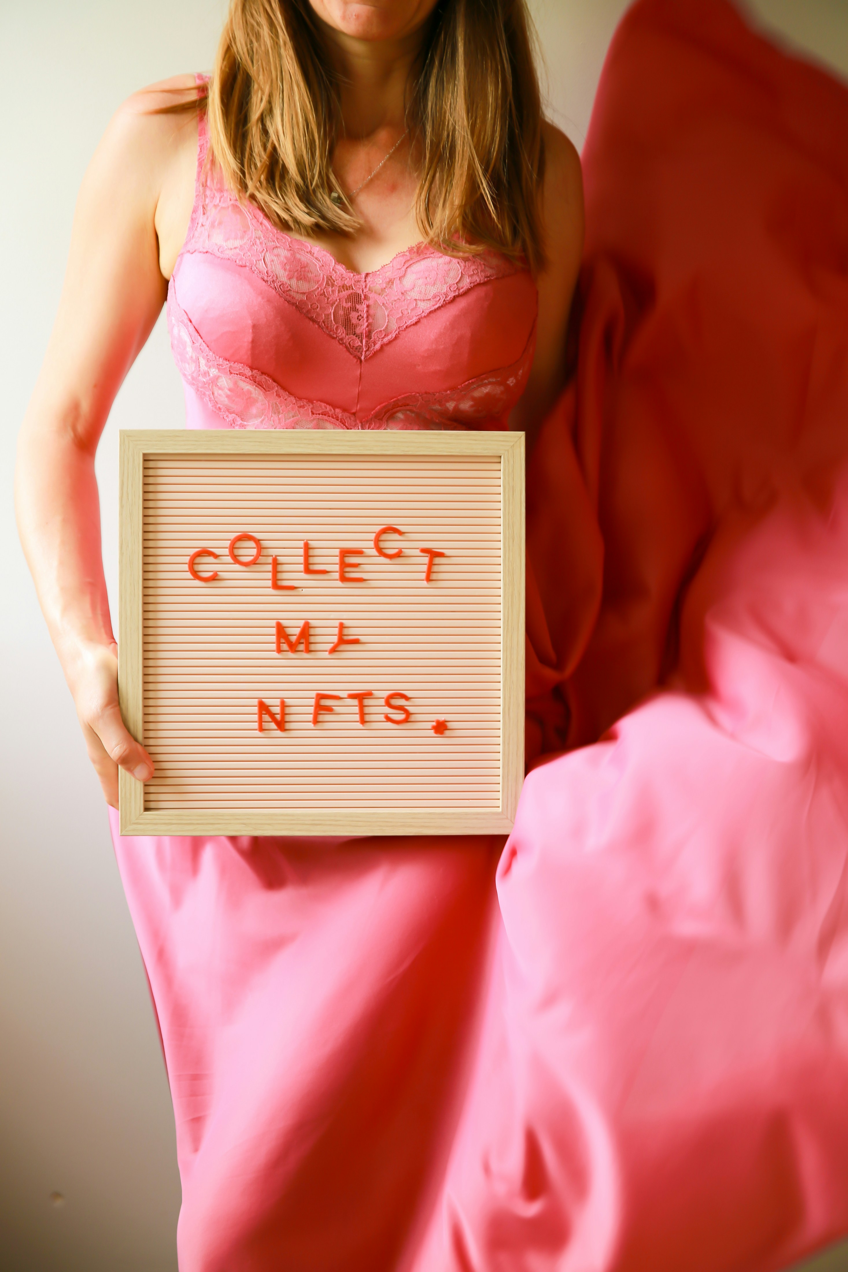 Woman holds sign that says "collect my nfts."