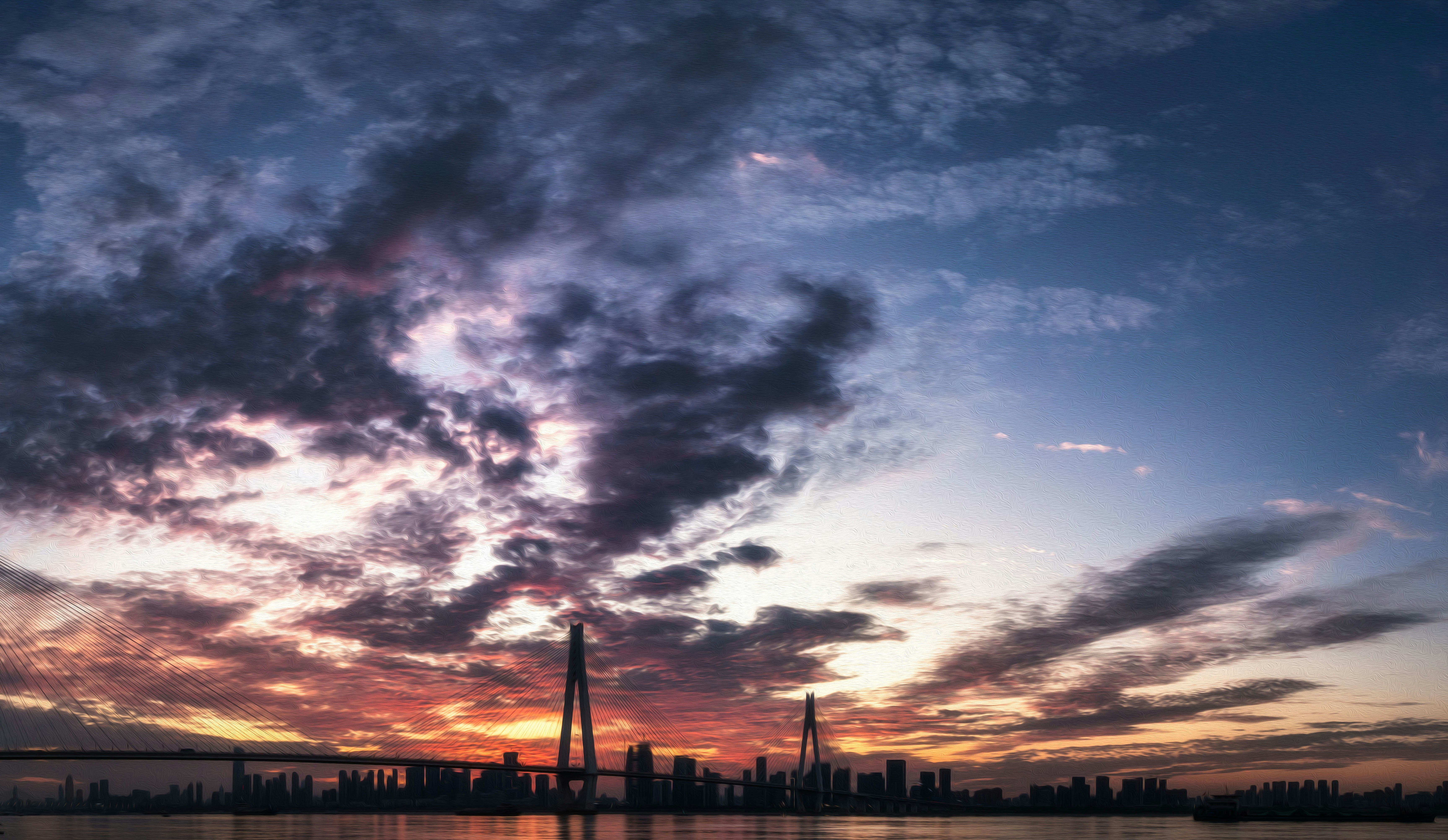 Dramatic sunset over a city and bridge.