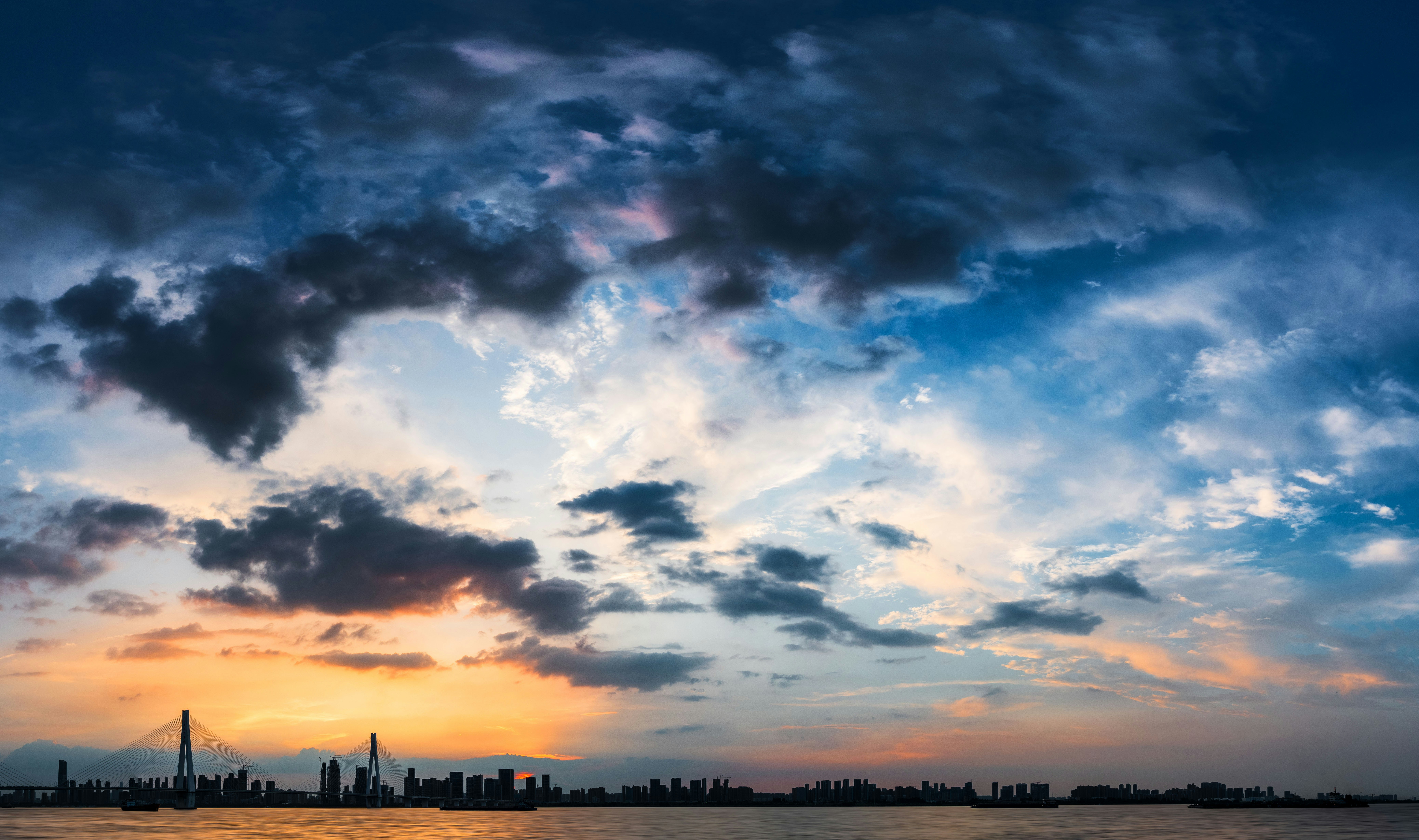 Dramatic sunset sky over a city skyline.