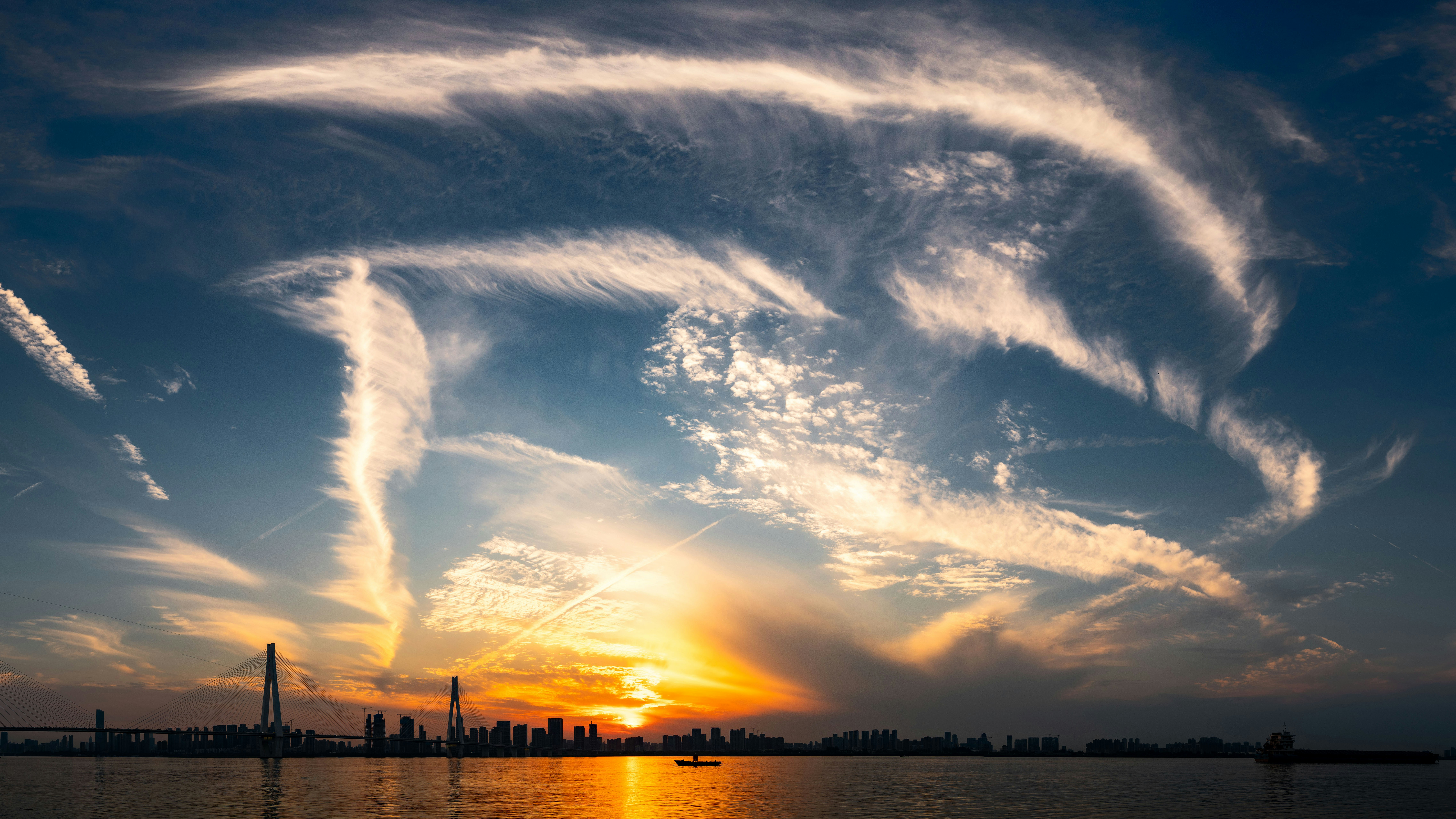 Dramatic clouds and a sunset over the water.