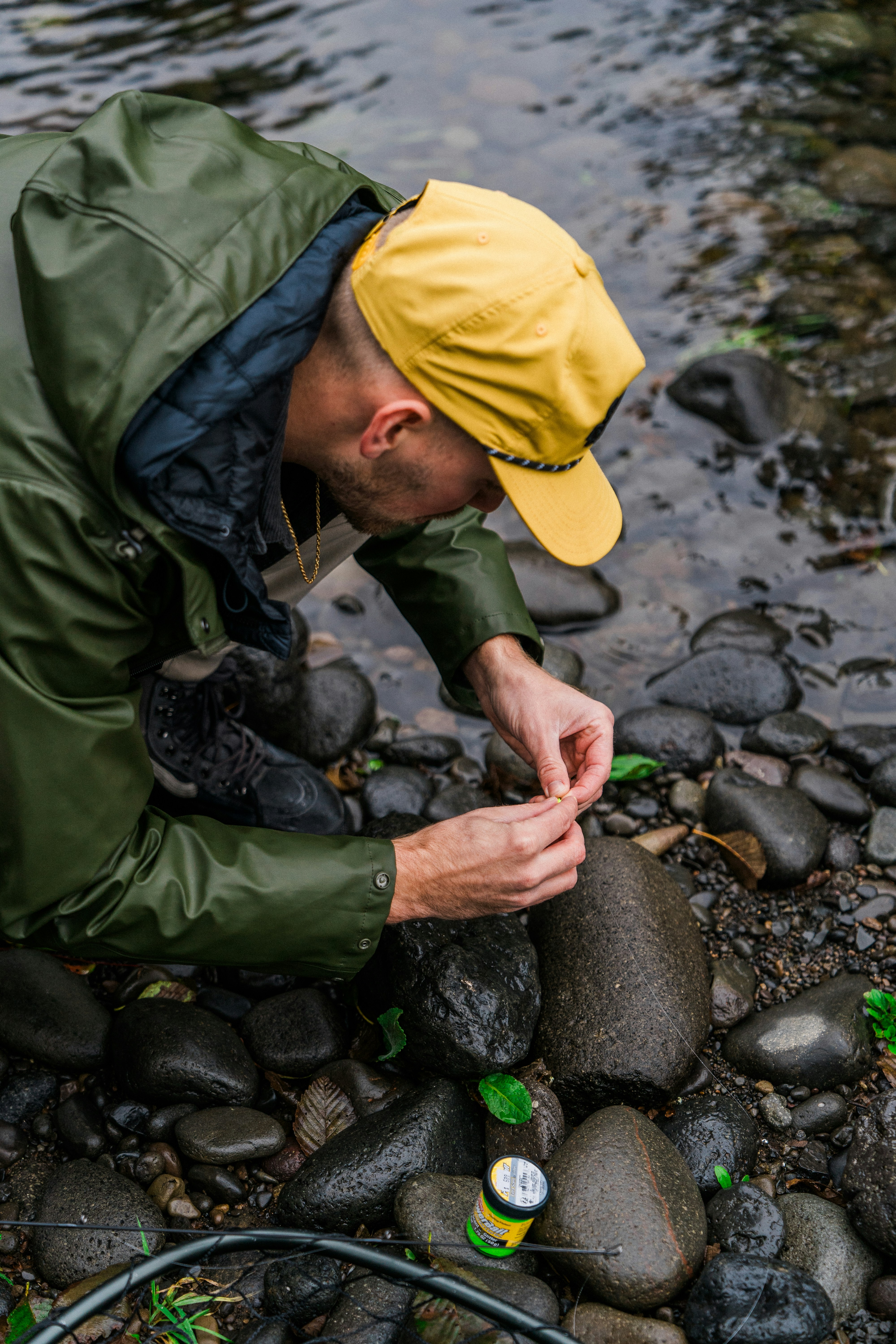 A man prepares his fishing line by the river.