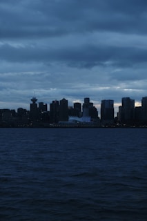 A dark silhouette of a city over water.