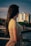 A woman looks towards the city buildings.