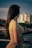 A woman looks towards the city buildings.