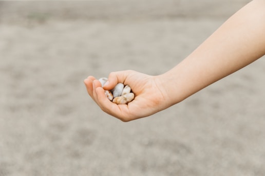 A child holds small, smooth stones in their hand.