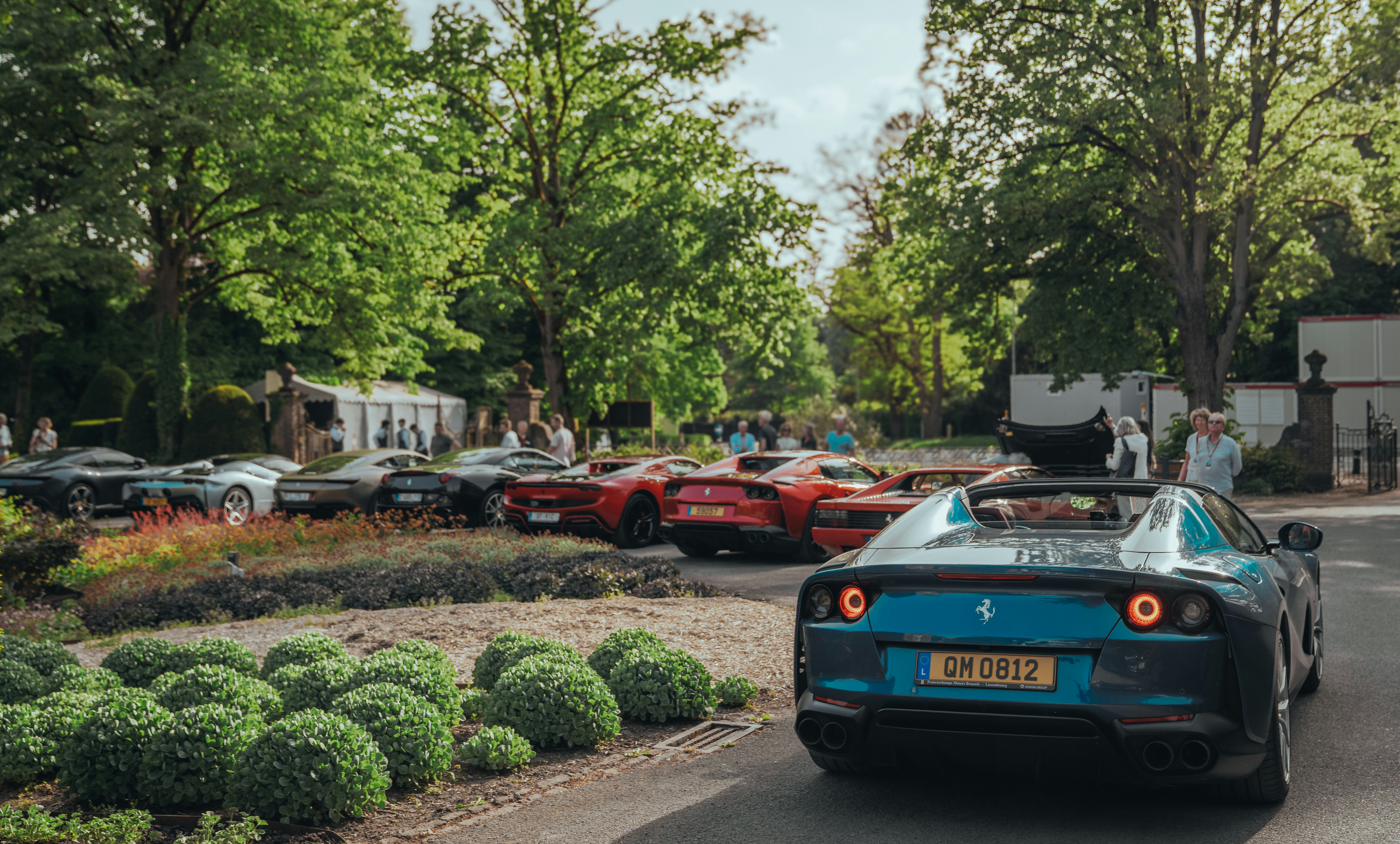 Luxury cars are parked outside.