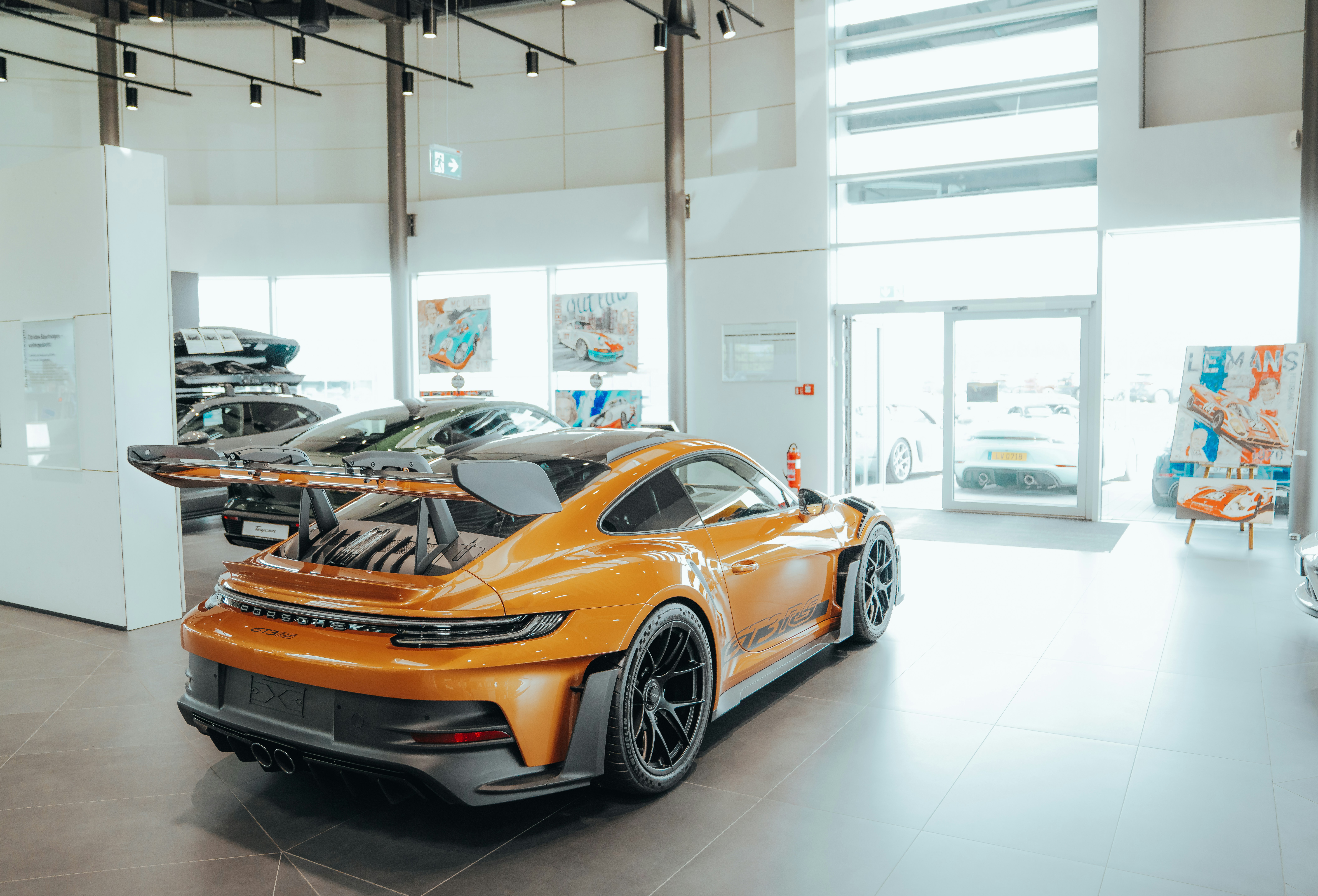 A bright orange porsche inside a showroom.