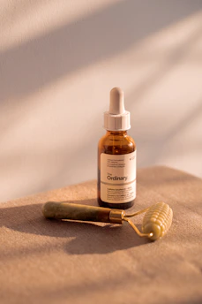 Skincare serum and facial roller on a neutral surface.