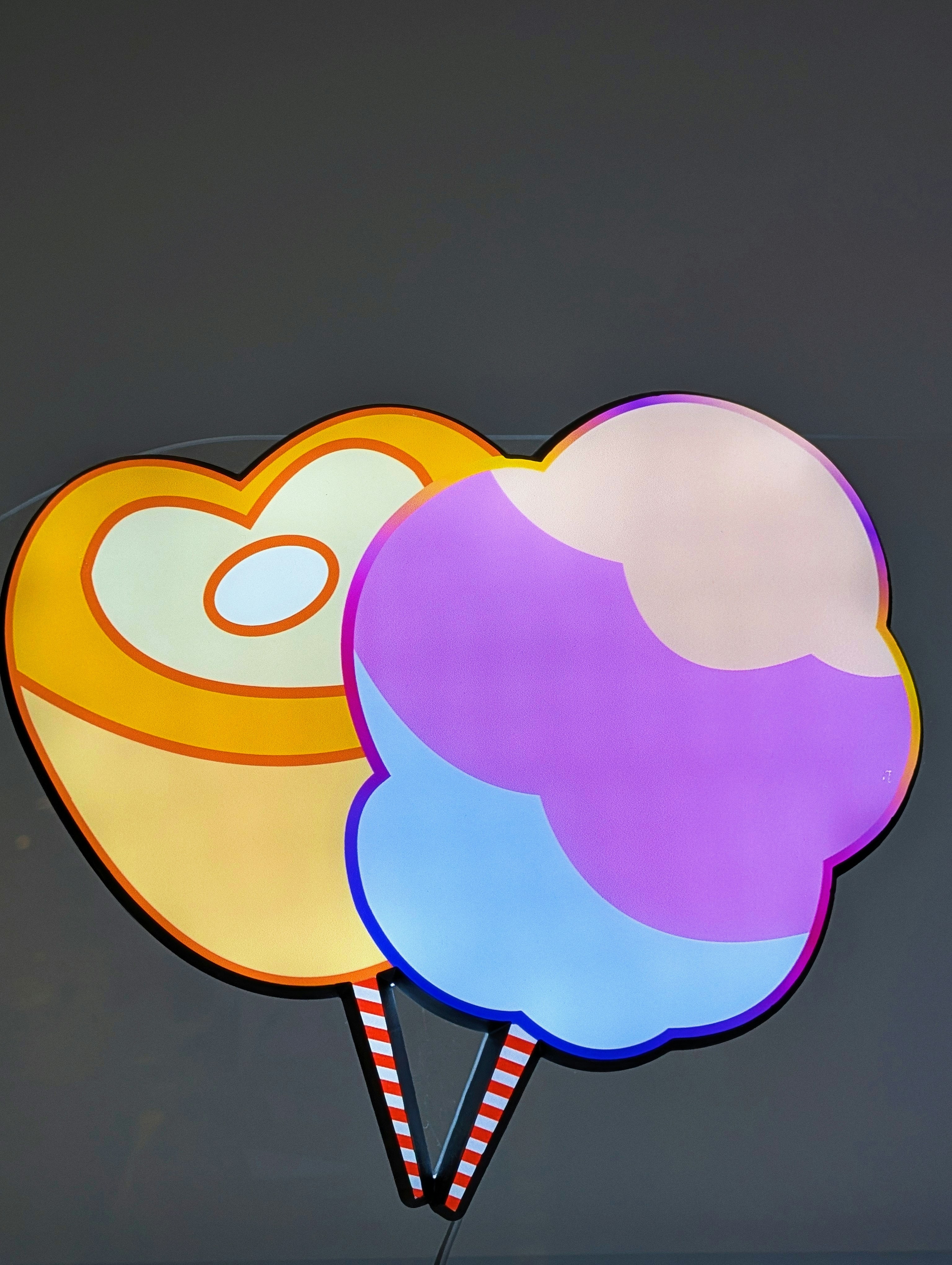 Algodão doce e uma guloseima em forma de coração estão brilhando.