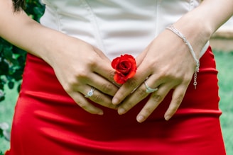 A woman gently holds a red rose.