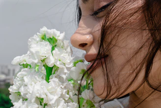 A woman is smelling a bunch of flowers.
