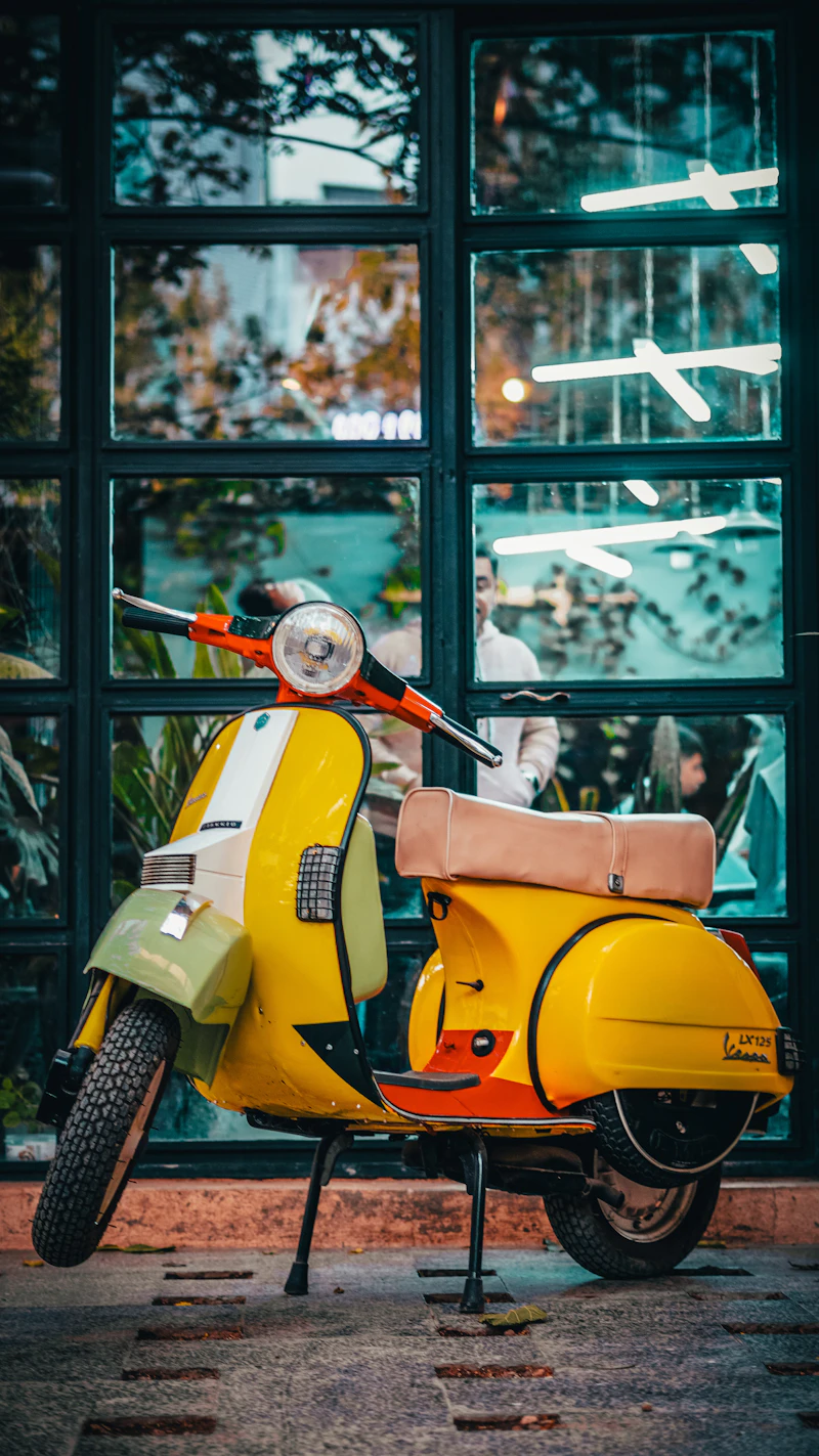 Vintage yellow Vespa scooter parked outside a classic barbershop