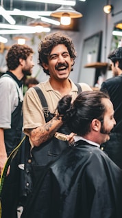 Barber laughs while cutting a client's hair.