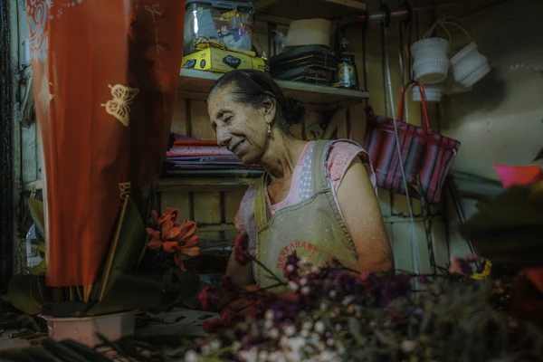 A flower shop owner smiling while arranging stems at her workbench