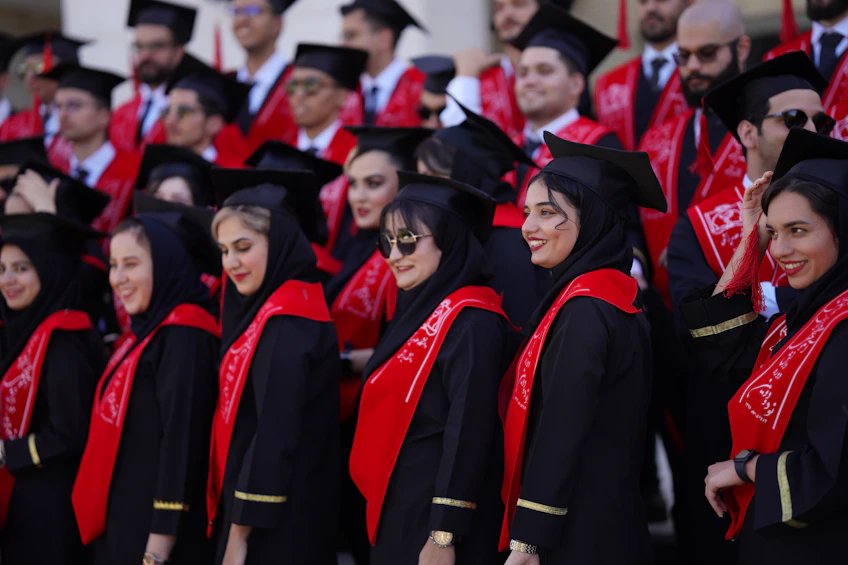 Graduates pose together, dressed in their robes.