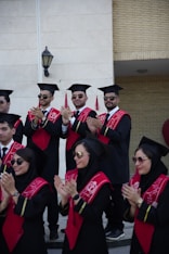 Graduates wearing caps and gowns are clapping.
