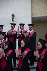 Graduates wearing caps and gowns are clapping.