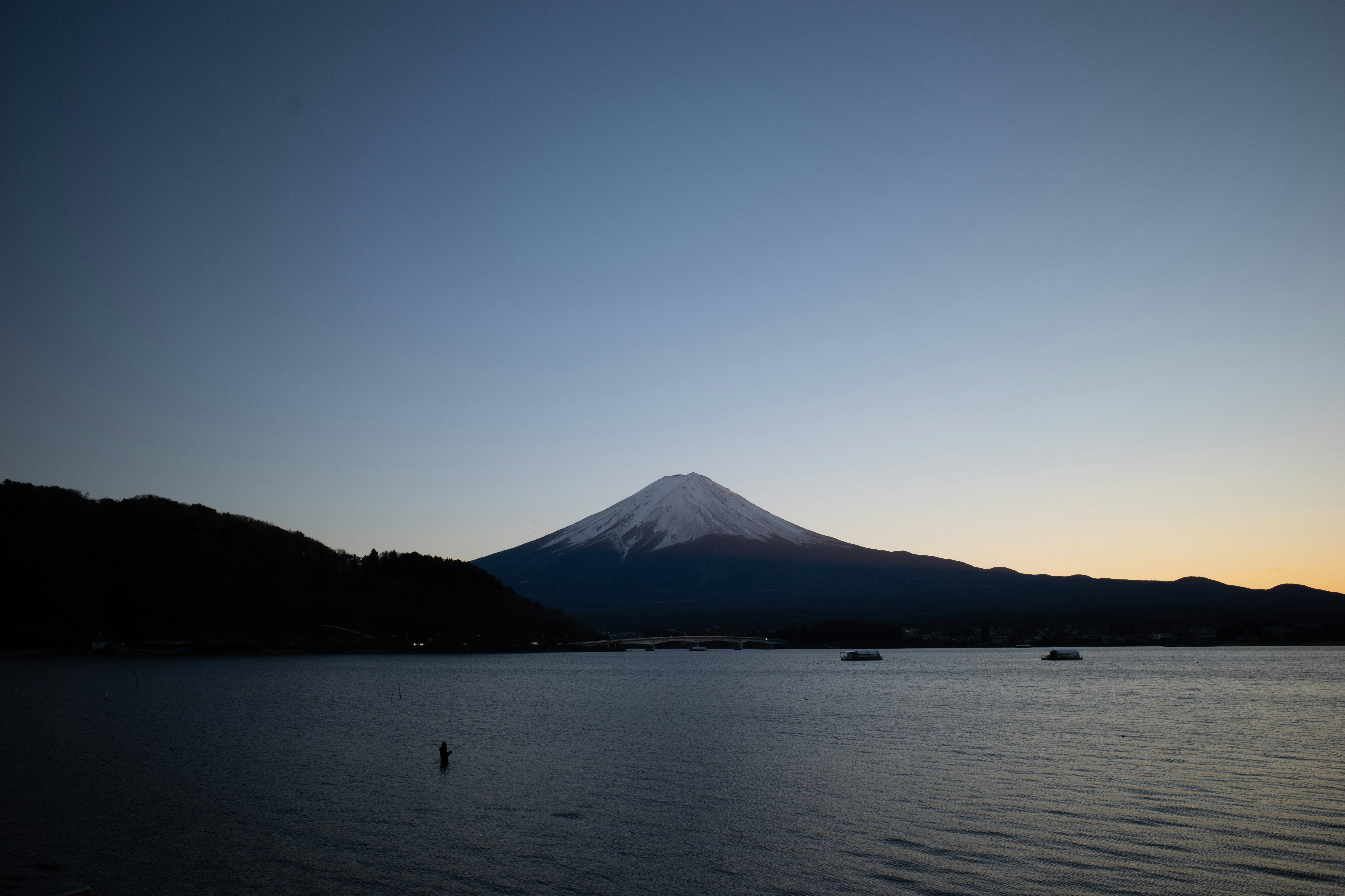 Mount fuji overlooks a calm lake at dusk.