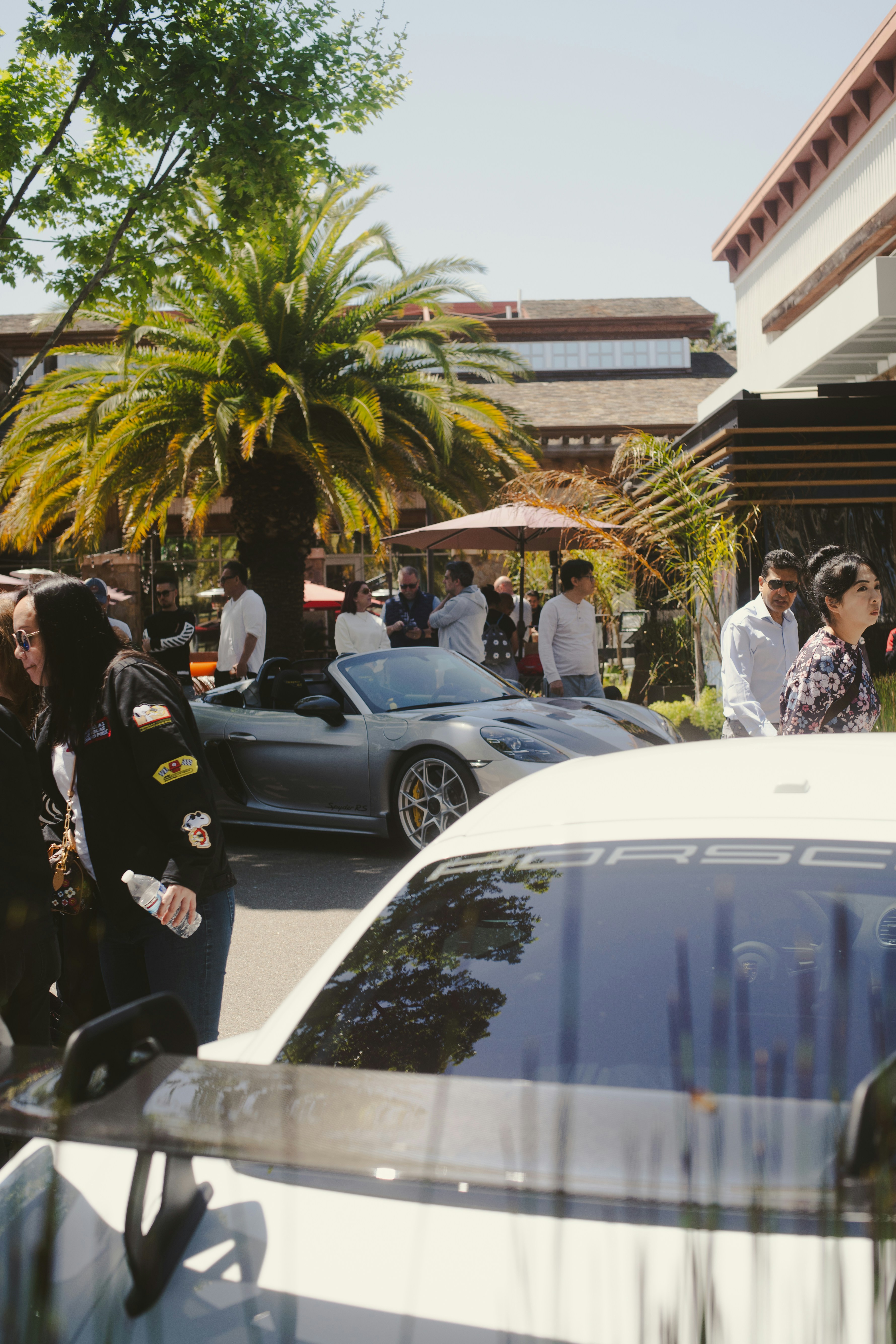 Luxury cars and people enjoying a sunny day.