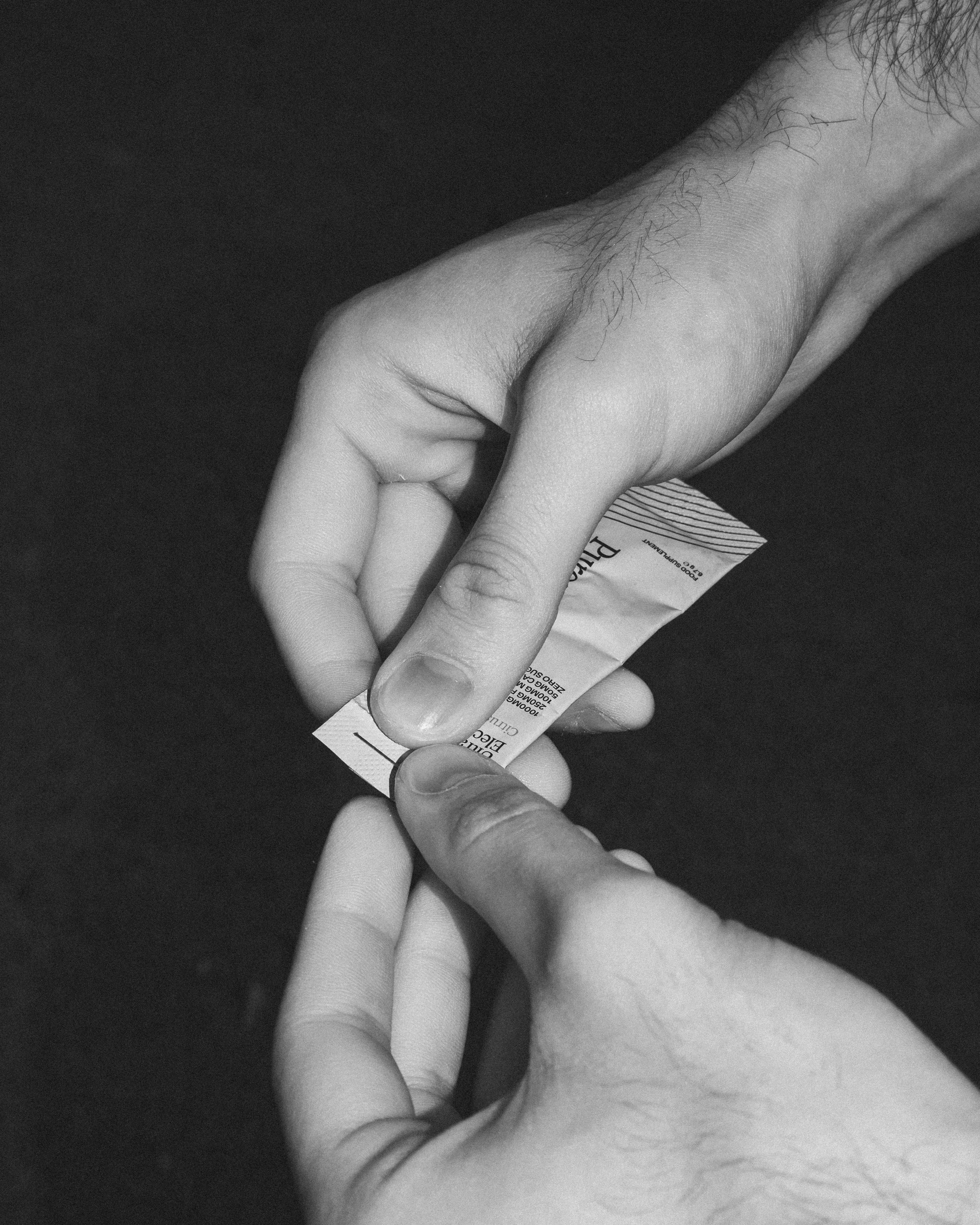 Hands are opening a packet of something.