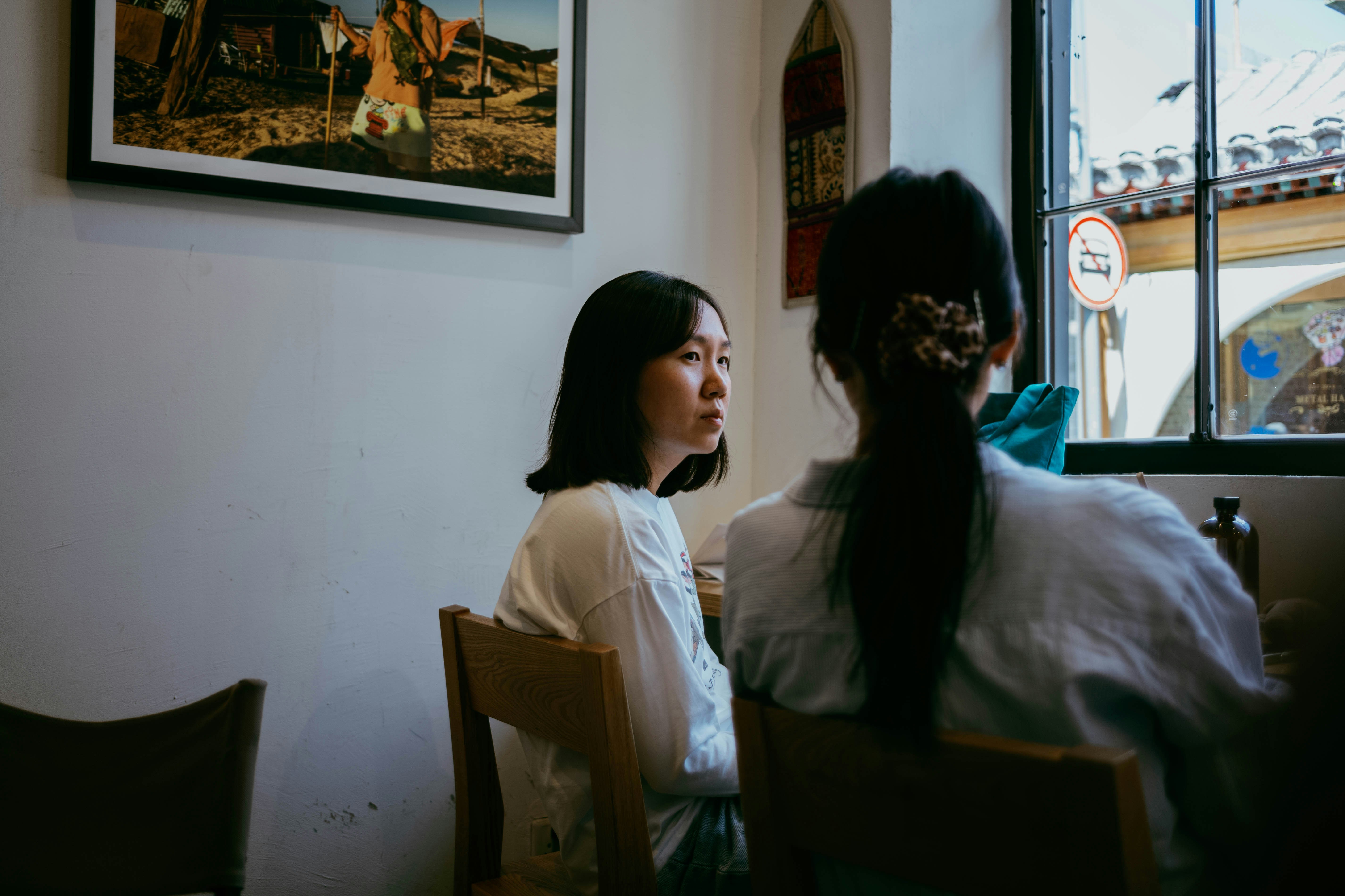 Two women sit and chat in a cozy cafe.
