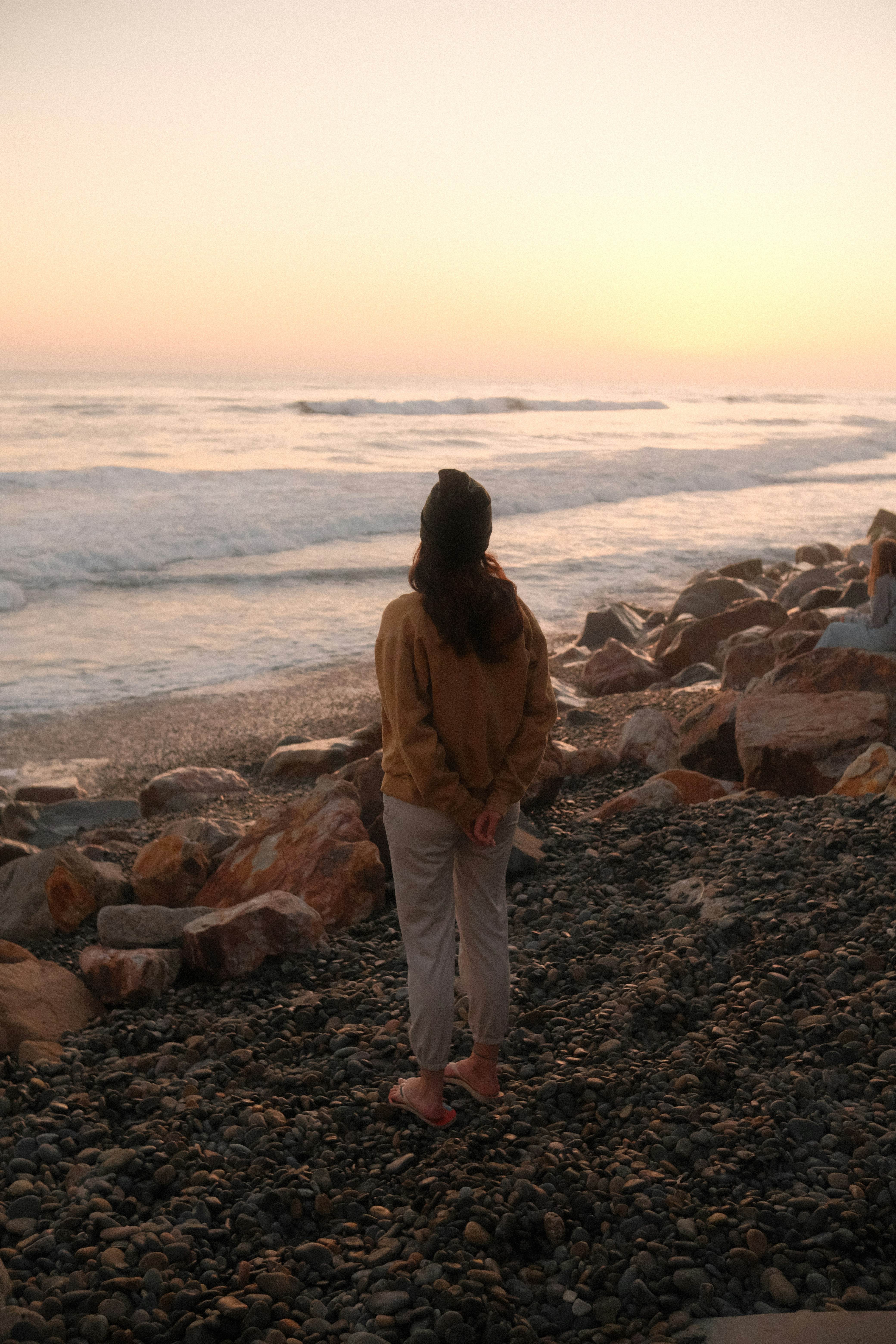A person gazes at the ocean at sunset.