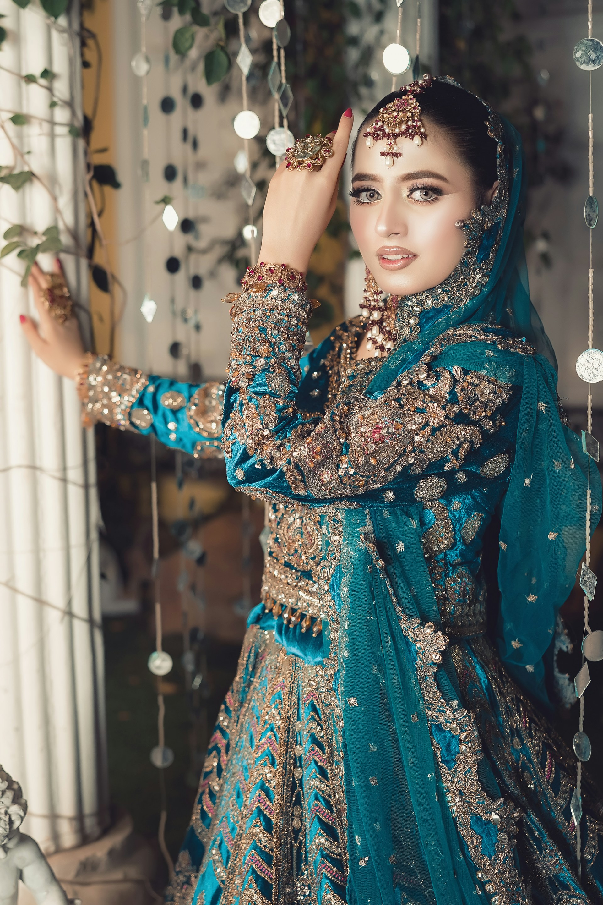 A beautiful woman poses in intricate, teal bridalwear.