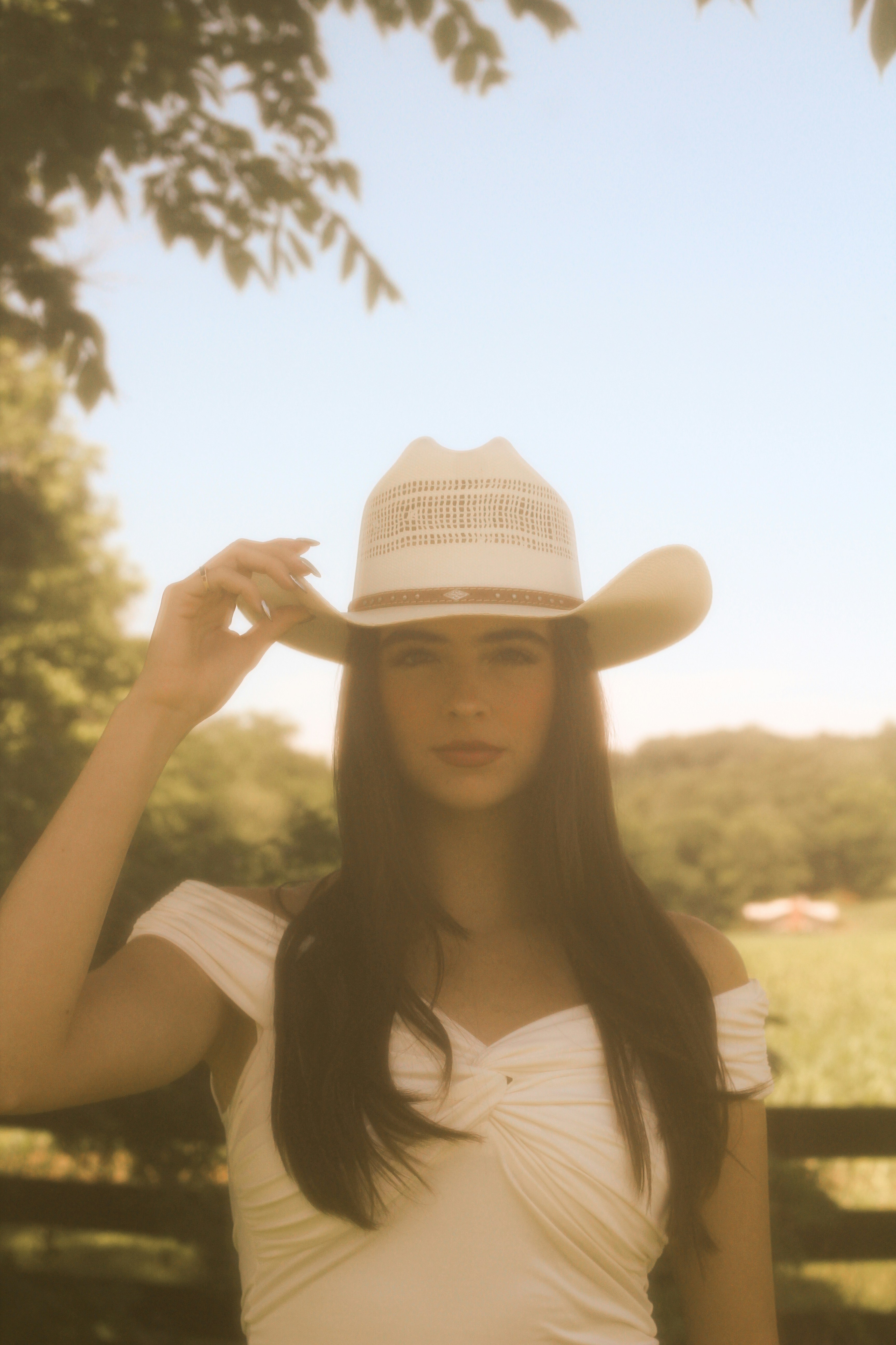 A young woman poses in a cowboy hat.
