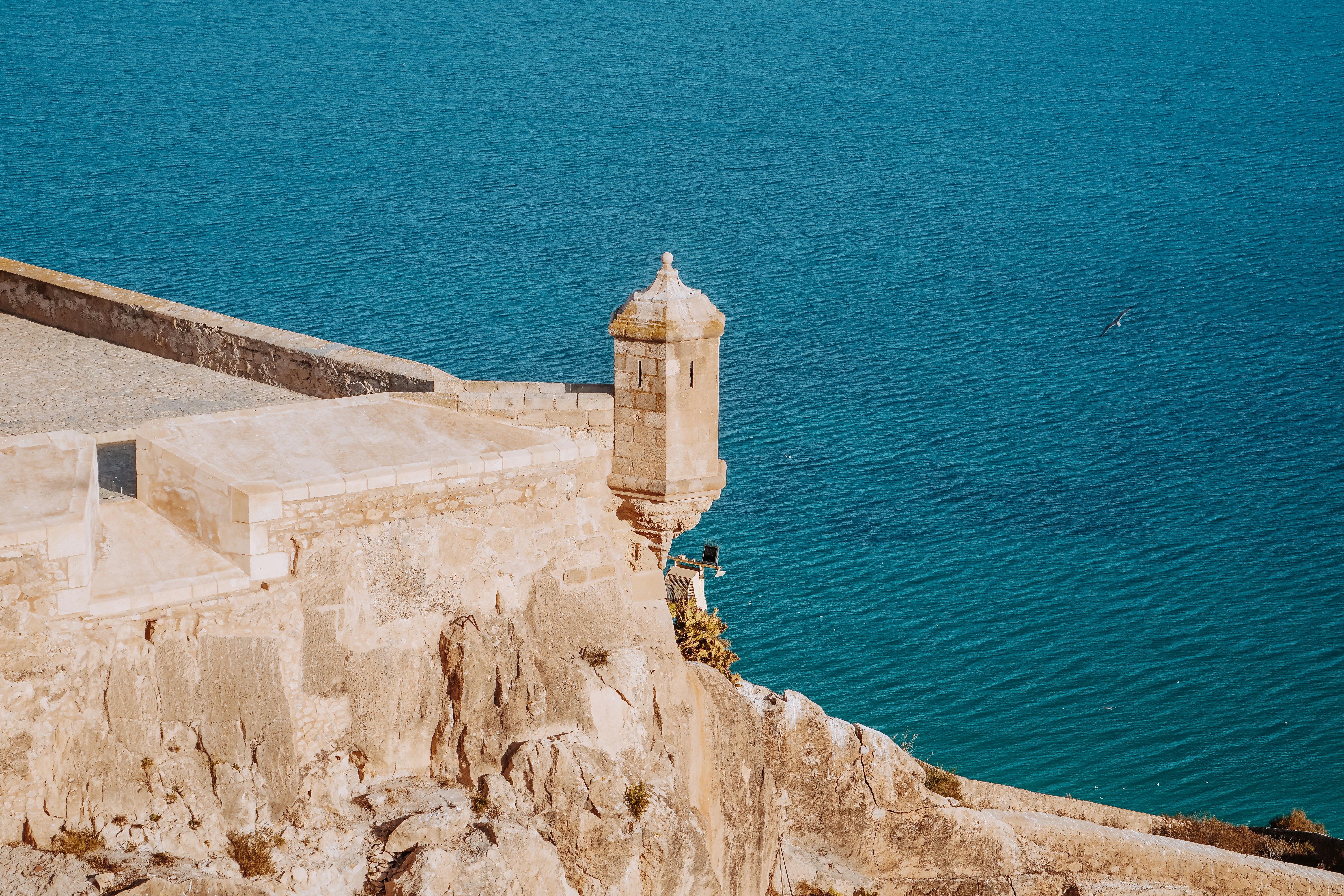 A stone structure overlooking blue water.